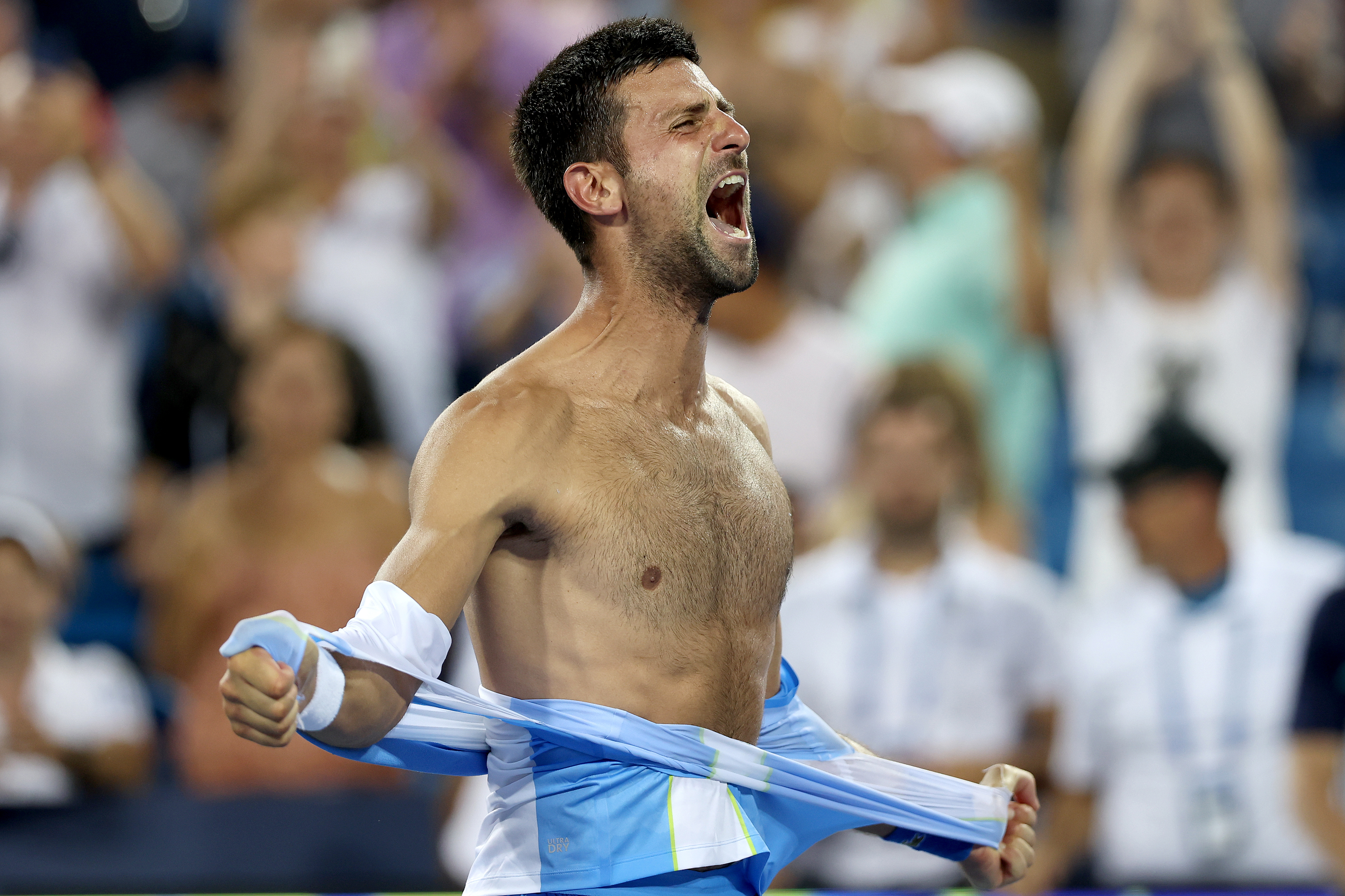 Novak Djokovic of Serbia tears his shirt off after defeating Carlos Alcaraz of Spain.