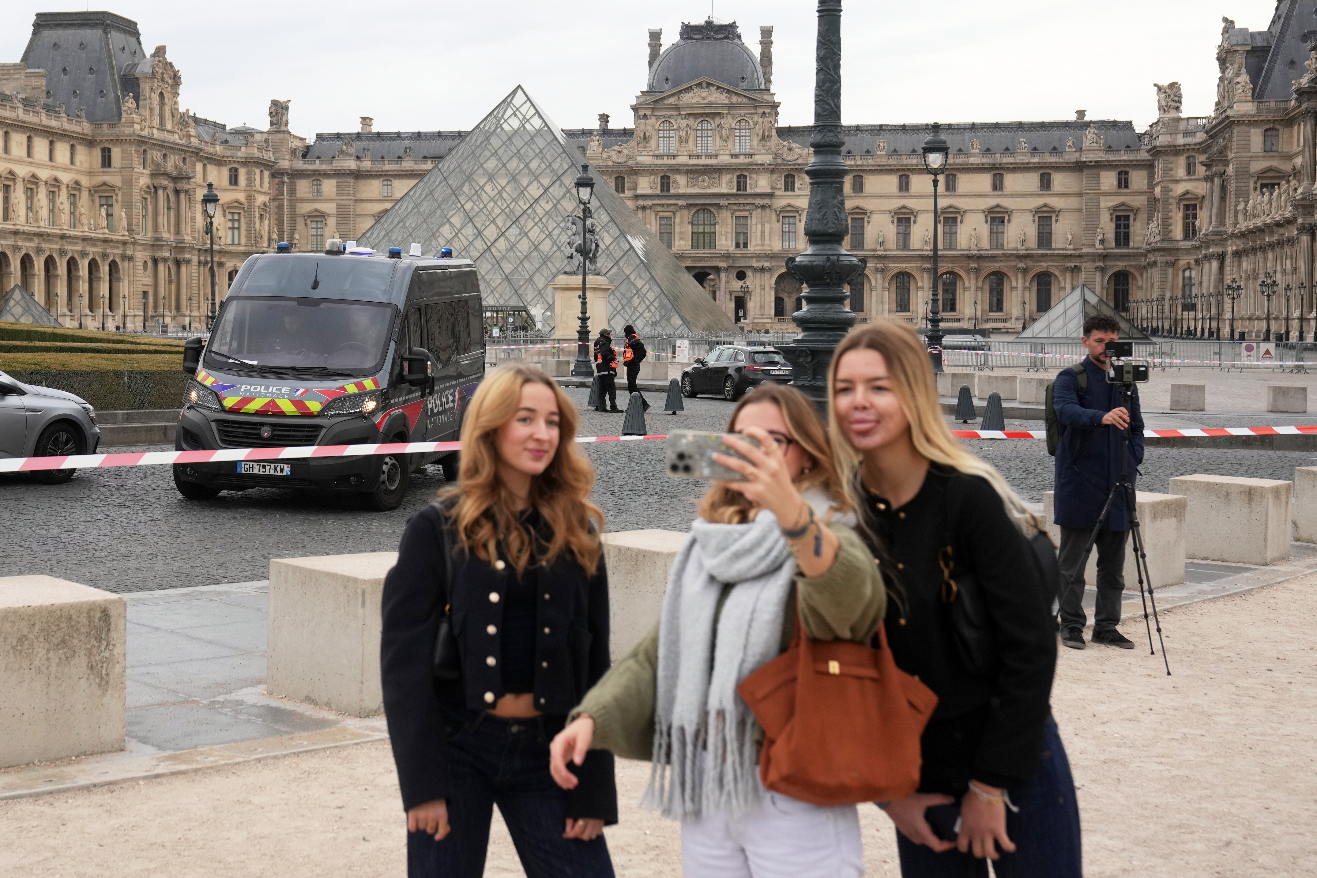 Tourists make a selfie in the courtyard of the closed Louvre museum after a robbery Sunday, Oct. 19, 2025 in Paris.