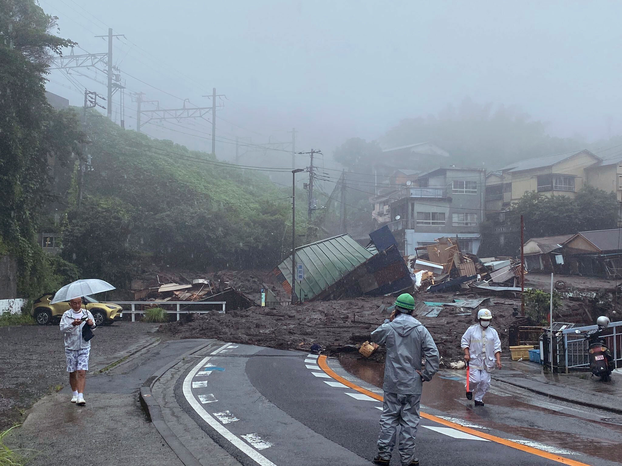 In this photo taken and provided by Satoru Watanabe, a road is covered by mud and debris following heavy rain in Atami city, Shizuoka prefecture, Saturday, July 3, 2021.