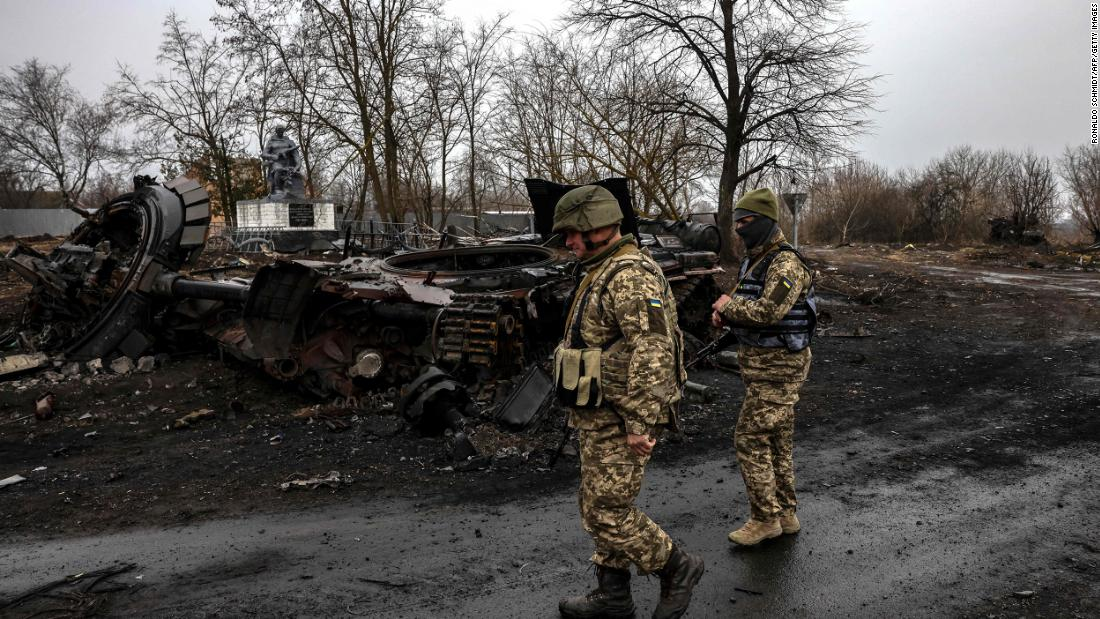 Ukrainian soldiers patrol next to a destroyed Russian tank in the village of Lukianivka near Kyiv. 