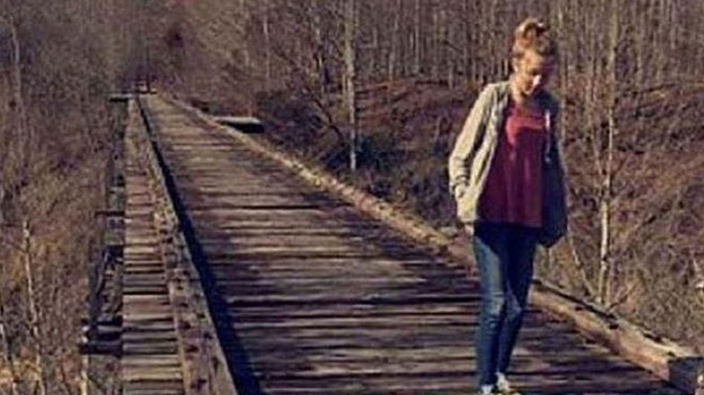 Una foto tomada de Abigail caminando por un puente de tren abandonado con una figura sombría que se cree que es el asesino en la distancia.