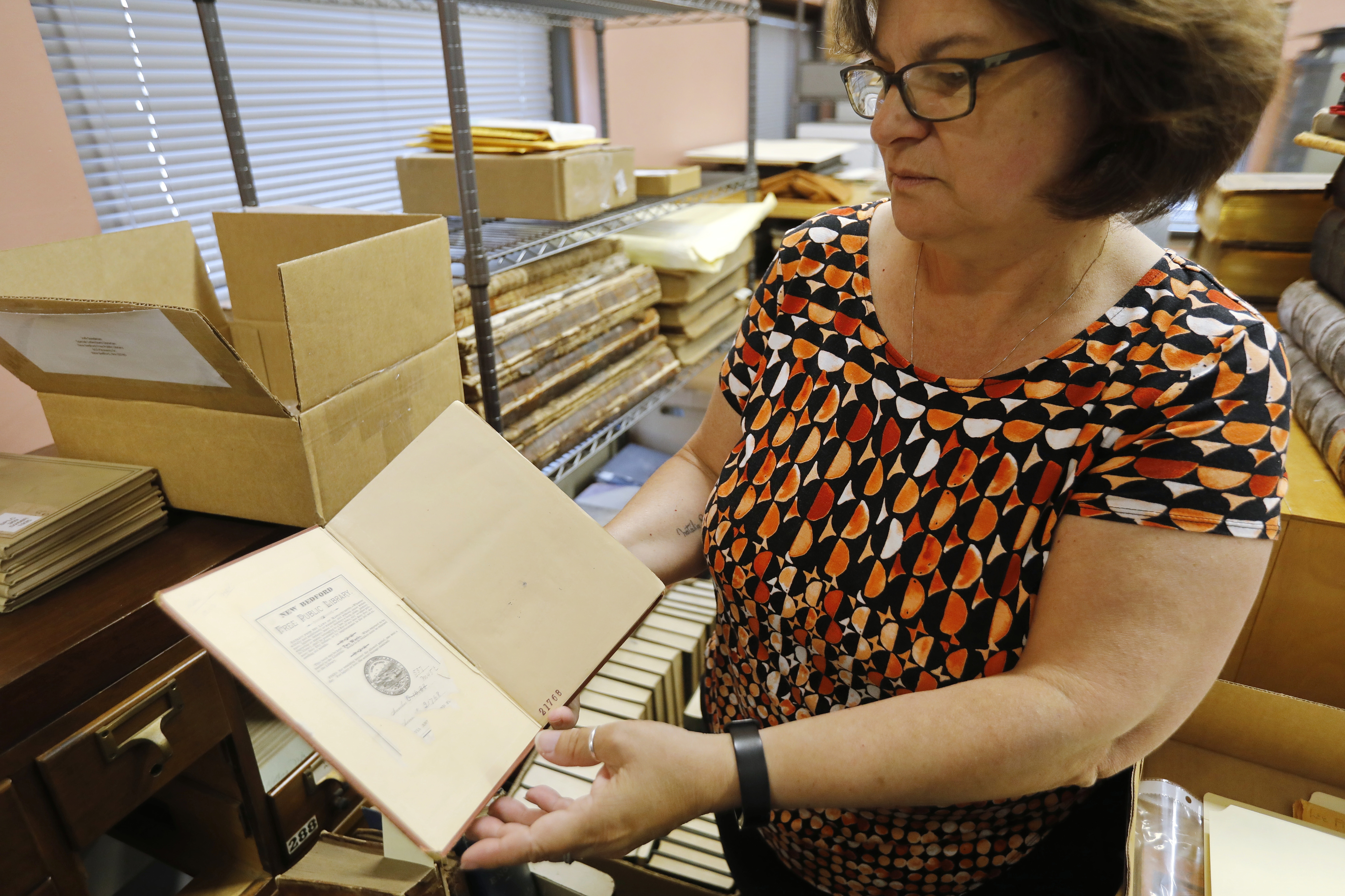 La directora de la Biblioteca Pública de New Bedford, Olivia Melo, echa un vistazo al libro con cien años de retraso el viernes 7 de julio de 2023. "Tratado elemental de electricidad" por James Clerk Maxwell fue devuelto a la biblioteca de la Universidad de West Virginia cien años después de que fuera sacado de la biblioteca pública de New Bedford en 1903.