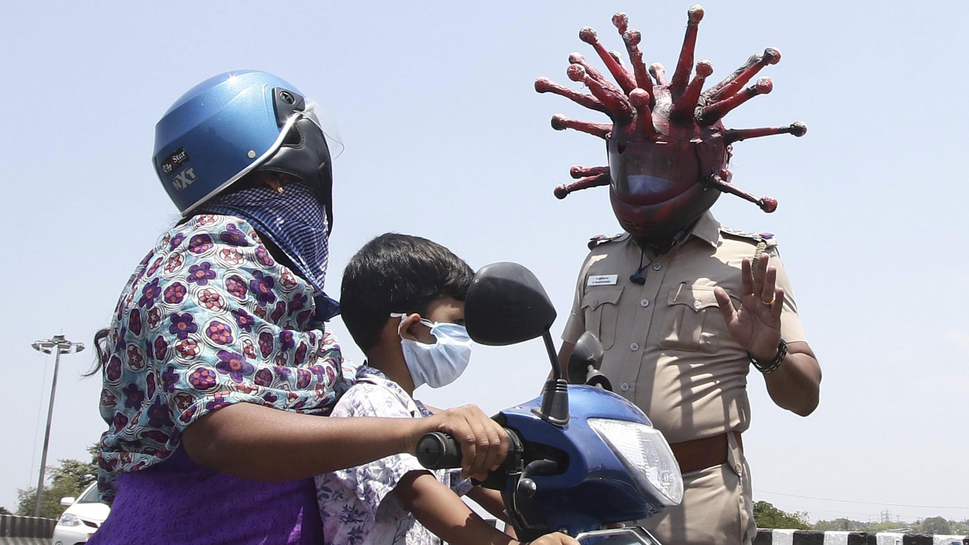 Police officer Rajesh Babu wears a helmet representing the coronavirus, and requests commuters to stay home during the 21-day countrywide lockdown.