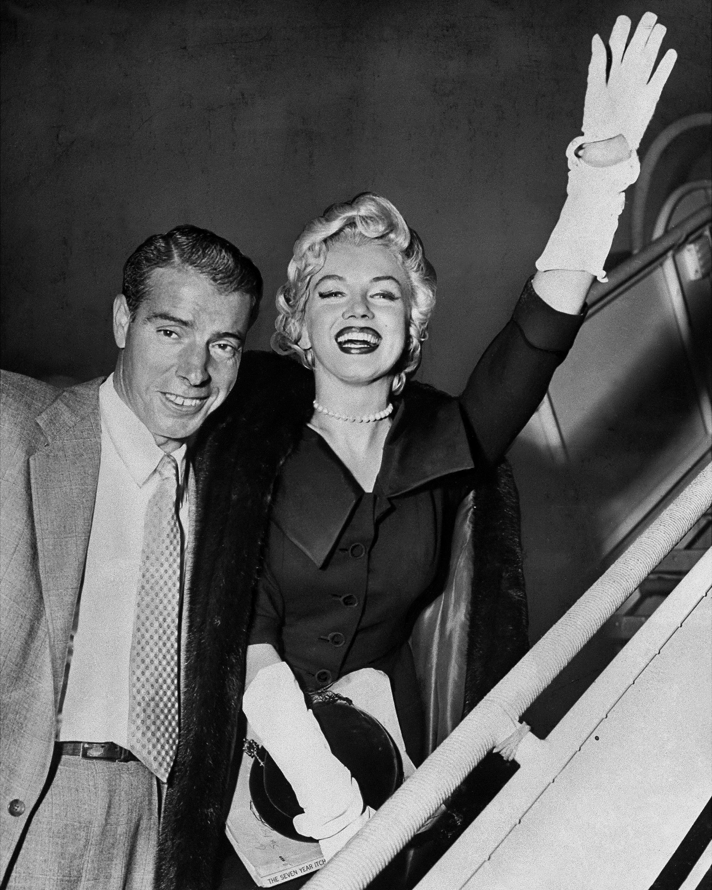 Joe DiMaggio and Marilyn Monroe as they board plane during their honeymoon to Japan in 1954. Marilyn Monroe is wearing a strand of pearls by Mikimoto, a wedding present from her husband.