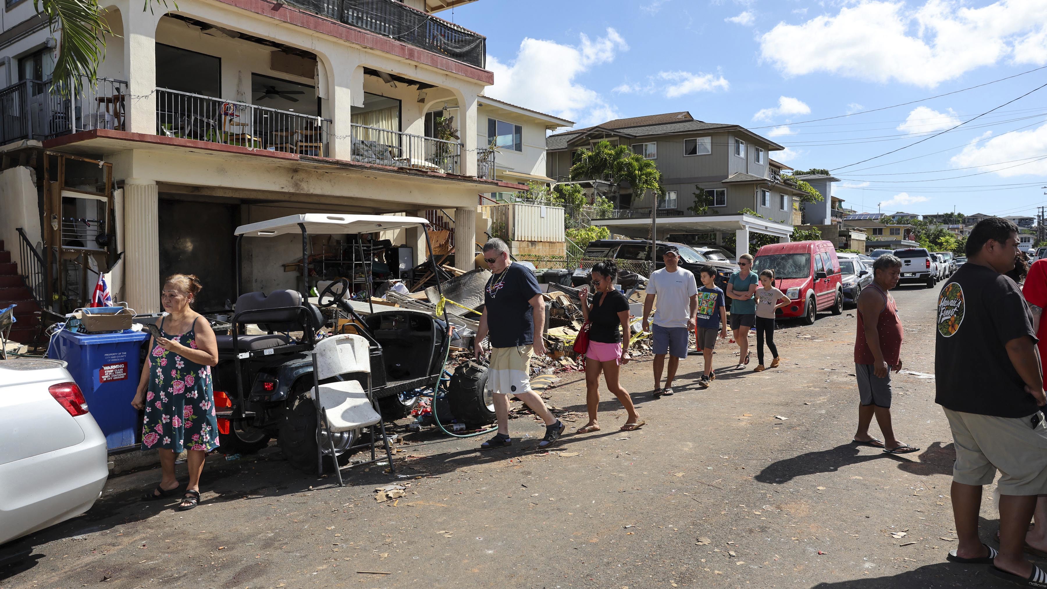 La gente pasa por la casa donde una explosión de fuegos artificiales en la víspera de Año Nuevo mató e hirió a varias personas en Honolulu, Hawaii.