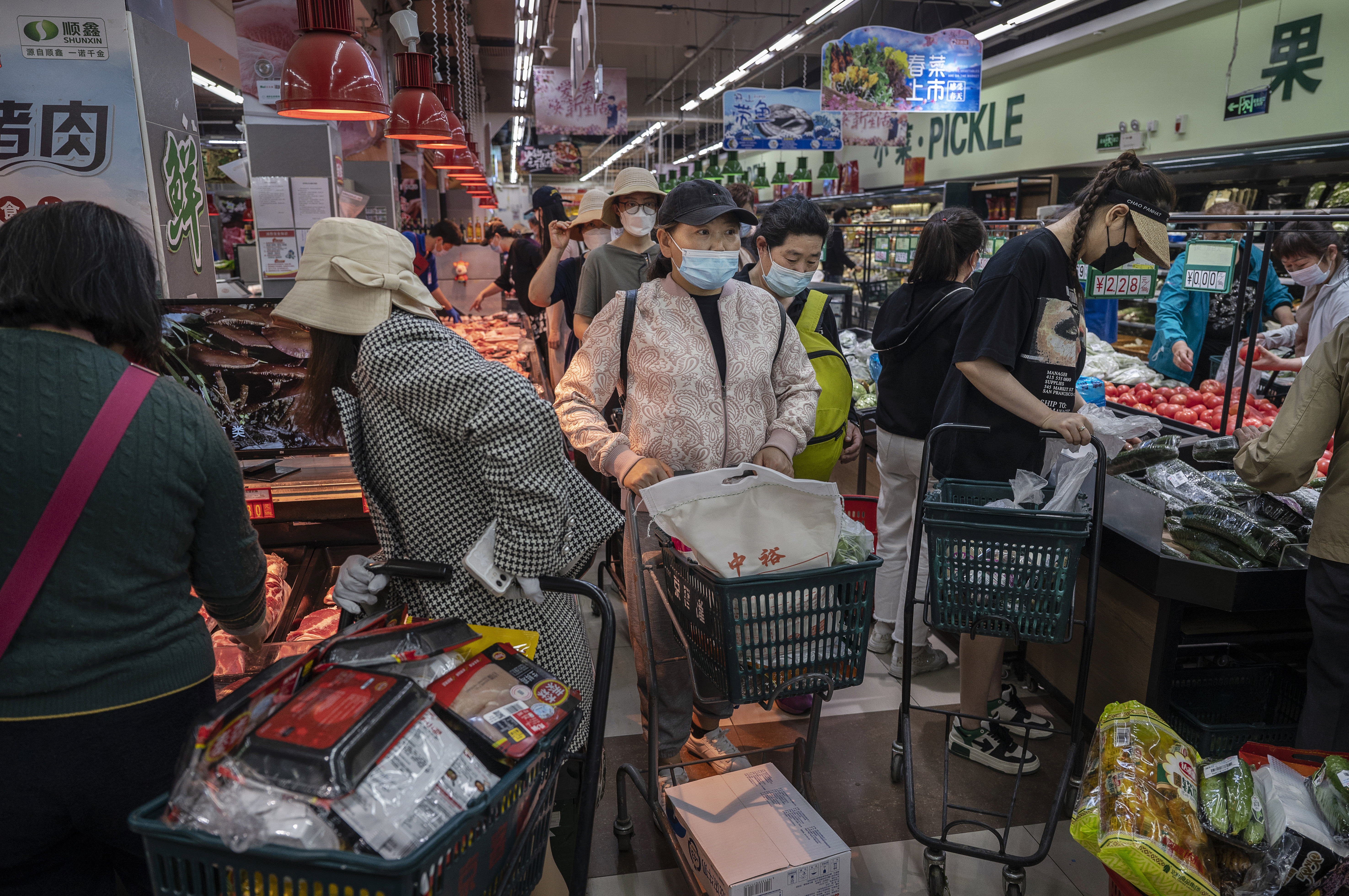 People crowd as they shop for food at a supermarket in Chaoyang District in Beijing, China