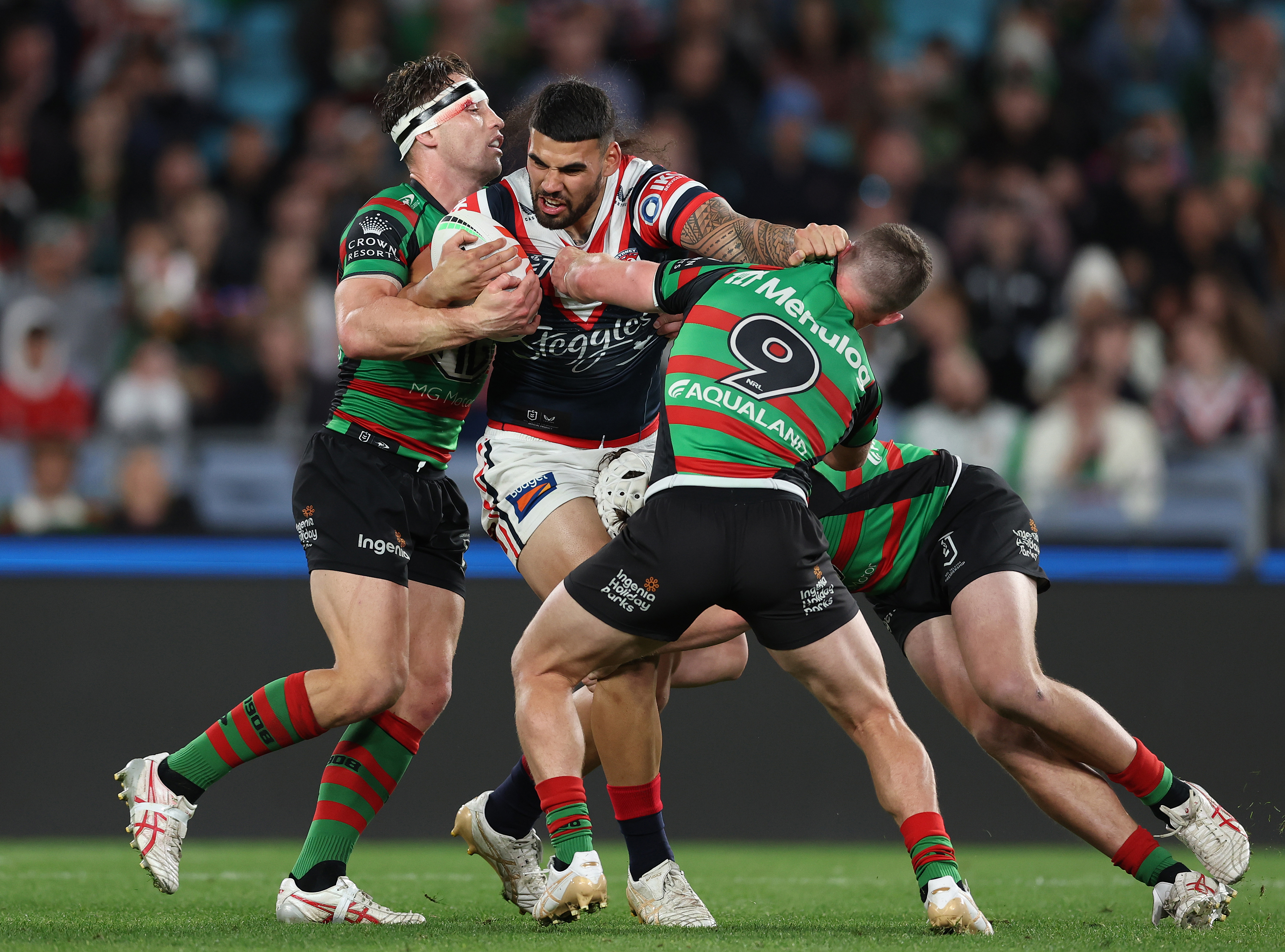 Terrell May of the Roosters attempts to bust through a two-man tackle against the Sydney Roosters. 