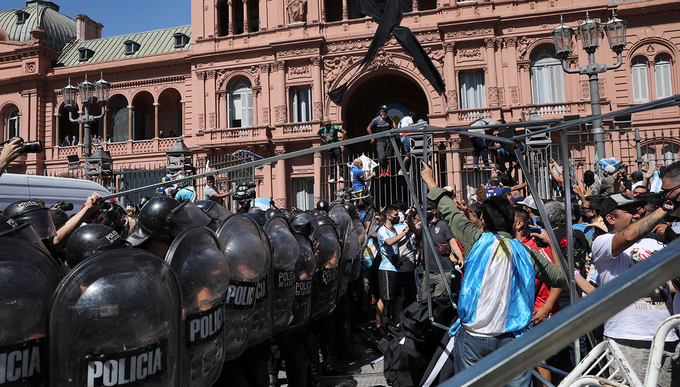 Soccer fans face off with police guarding the presidential palace, where Diego Maradona is lying in state, in Buenos Aires, Argentina.