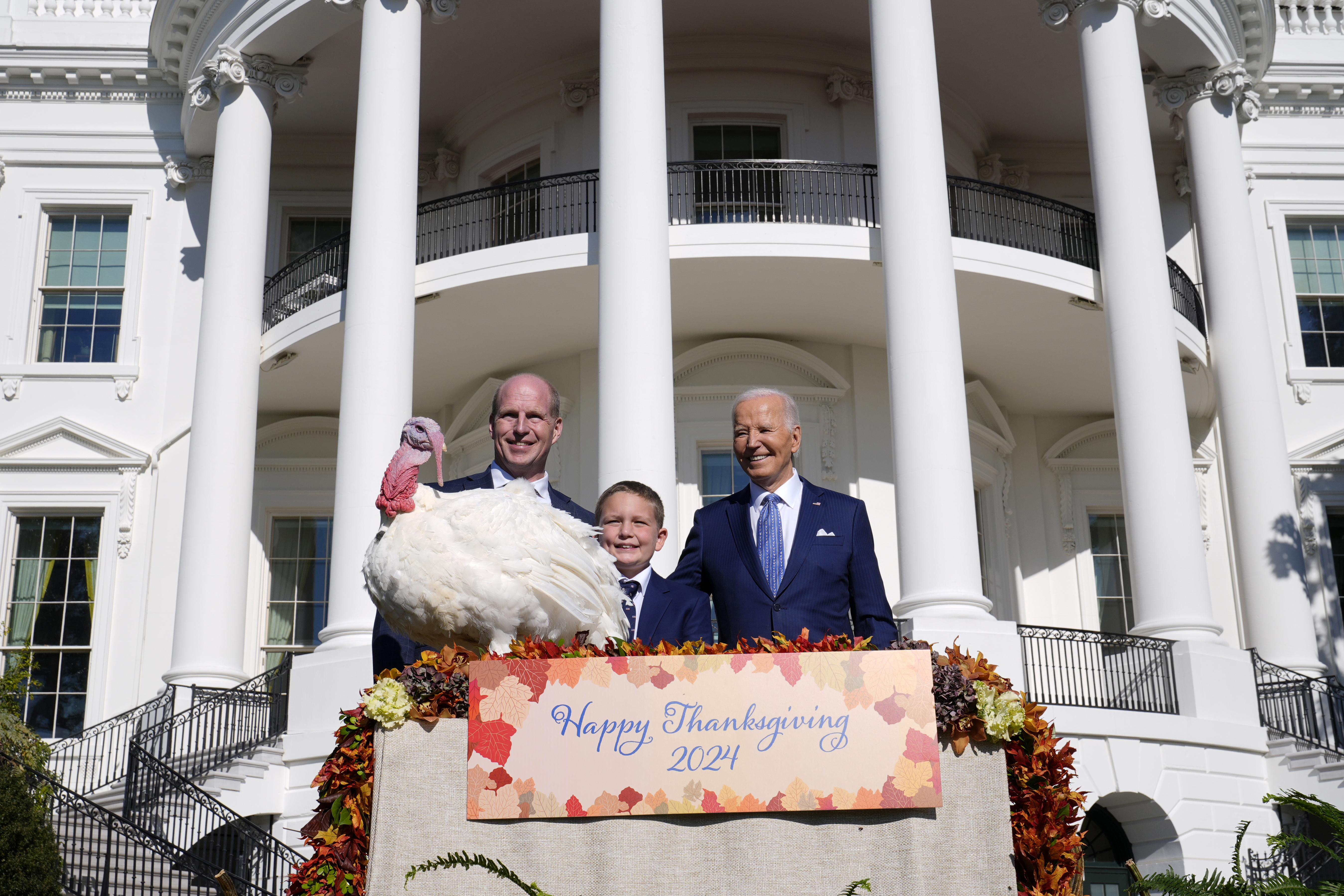 El presidente Joe Biden, a la derecha, junto a John Zimmerman, a la izquierda, presidente de la Federación Nacional del Pavo, su hijo Grant Zimmerman, al centro, y el pavo nacional del Día de Acción de Gracias, Peach, durante una ceremonia de indulto en el jardín sur de la Casa Blanca en Washington. Lunes 25 de noviembre de 2024. (Foto AP/Susan Walsh)