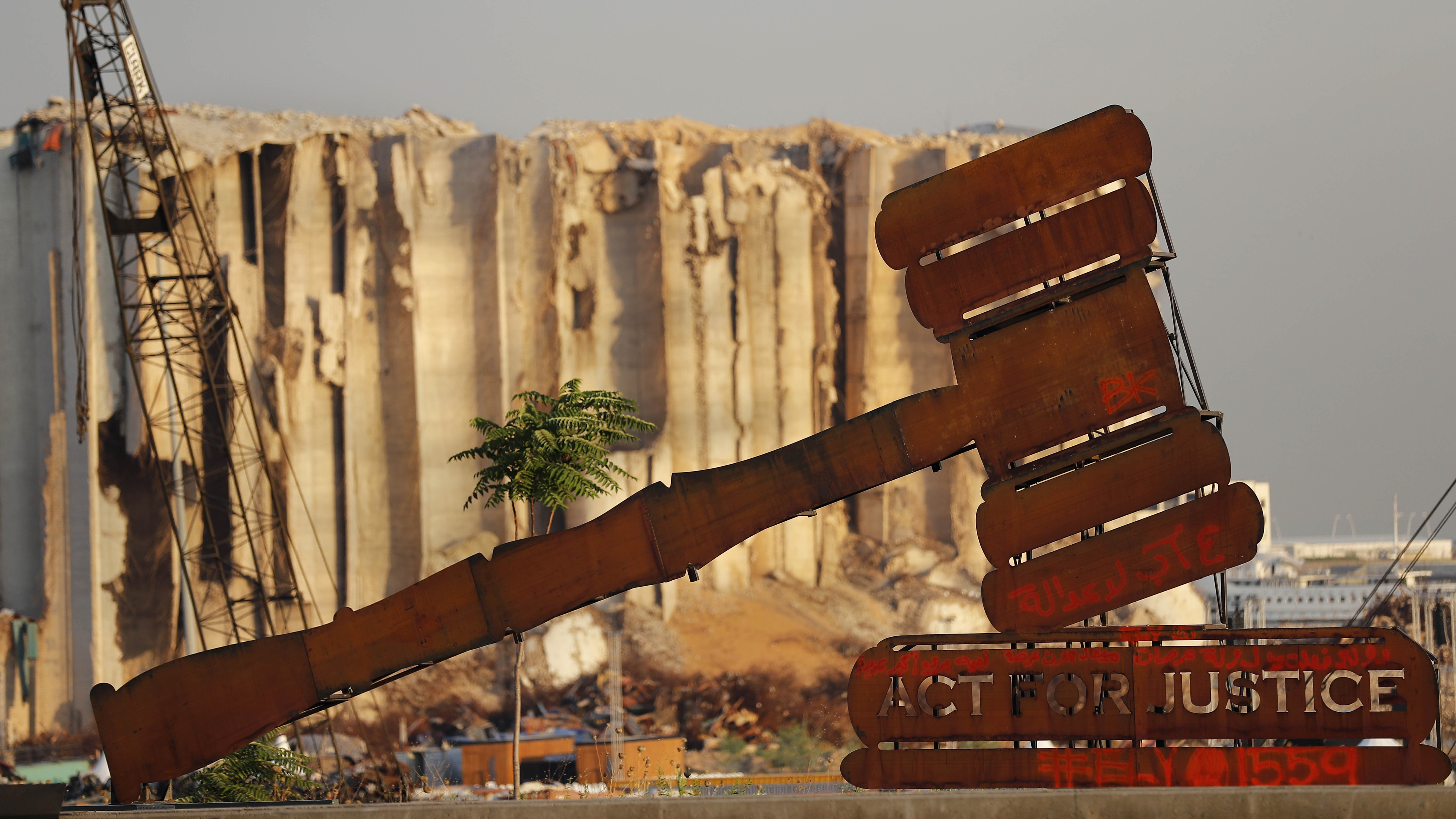 A justice symbol monument is seen in front of towering grain silos that were gutted in the massive August 2020 explosion at the port that claimed the lives of more than 200 people, in Beirut, Lebanon.