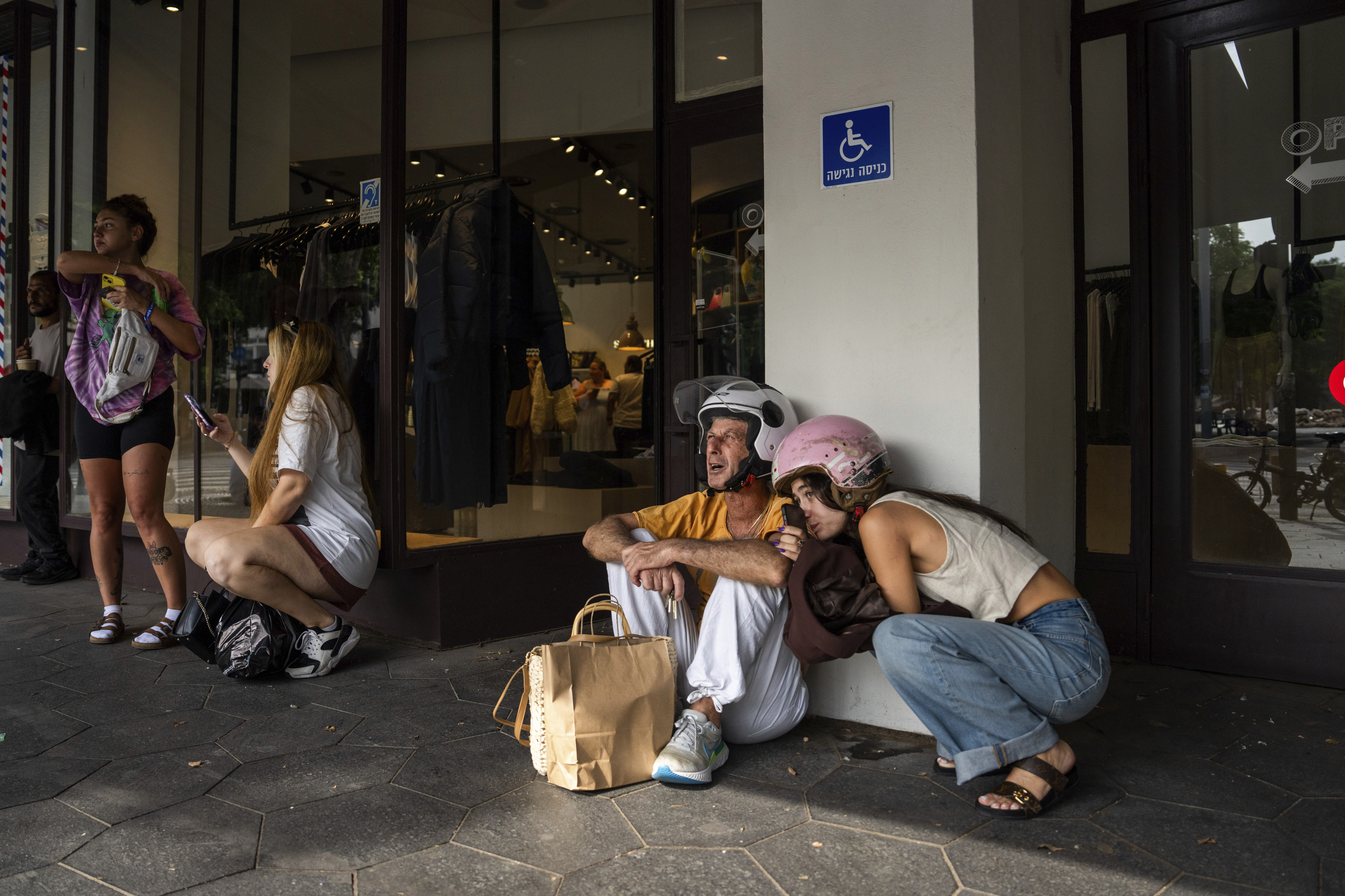 Israelis take cover as a siren warns of incoming rockets fired from the Gaza Strip, in Tel Aviv, Israel, Friday, Oct. 27, 2023.