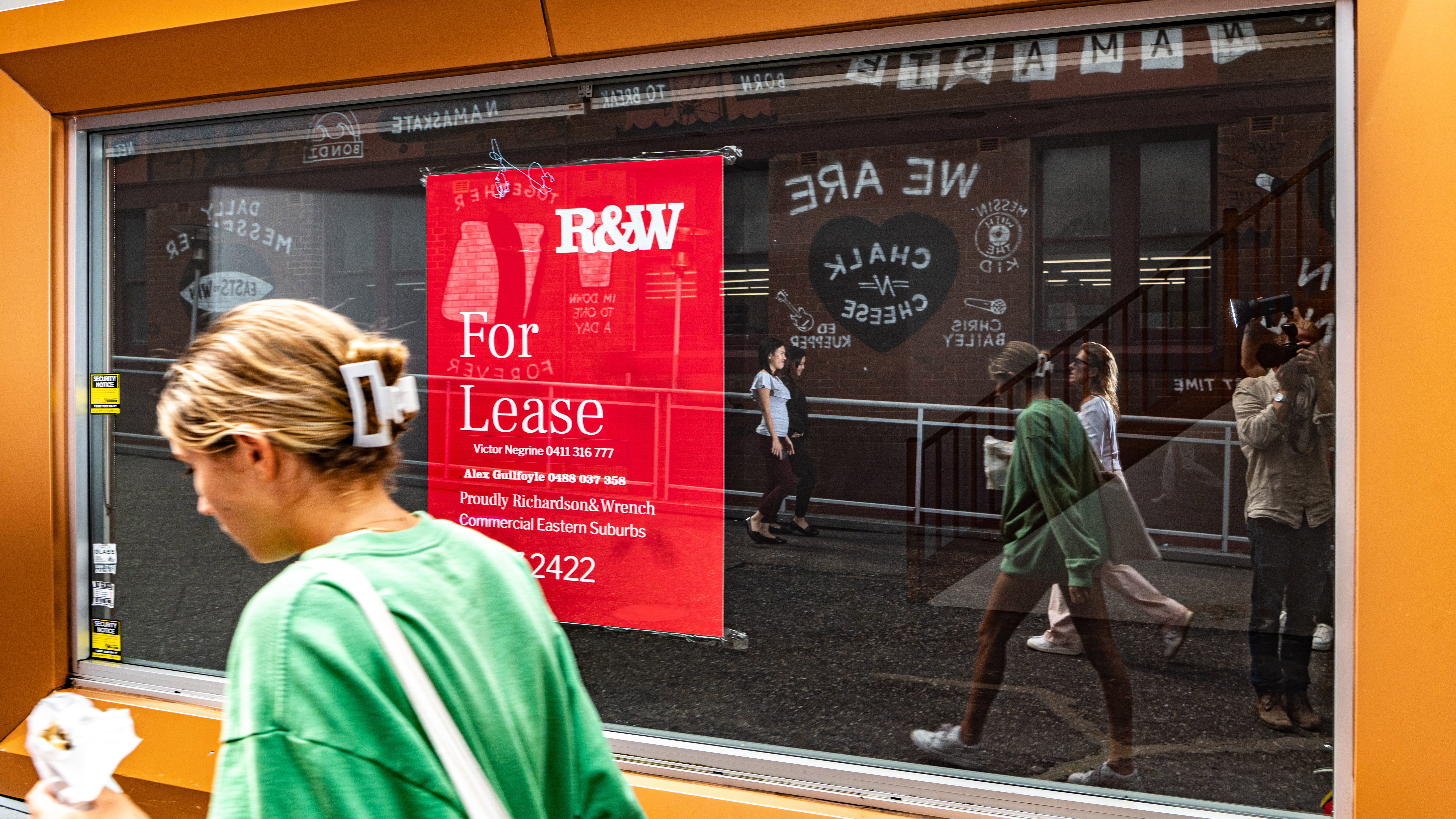 A woman walks past a for lease sign. 
