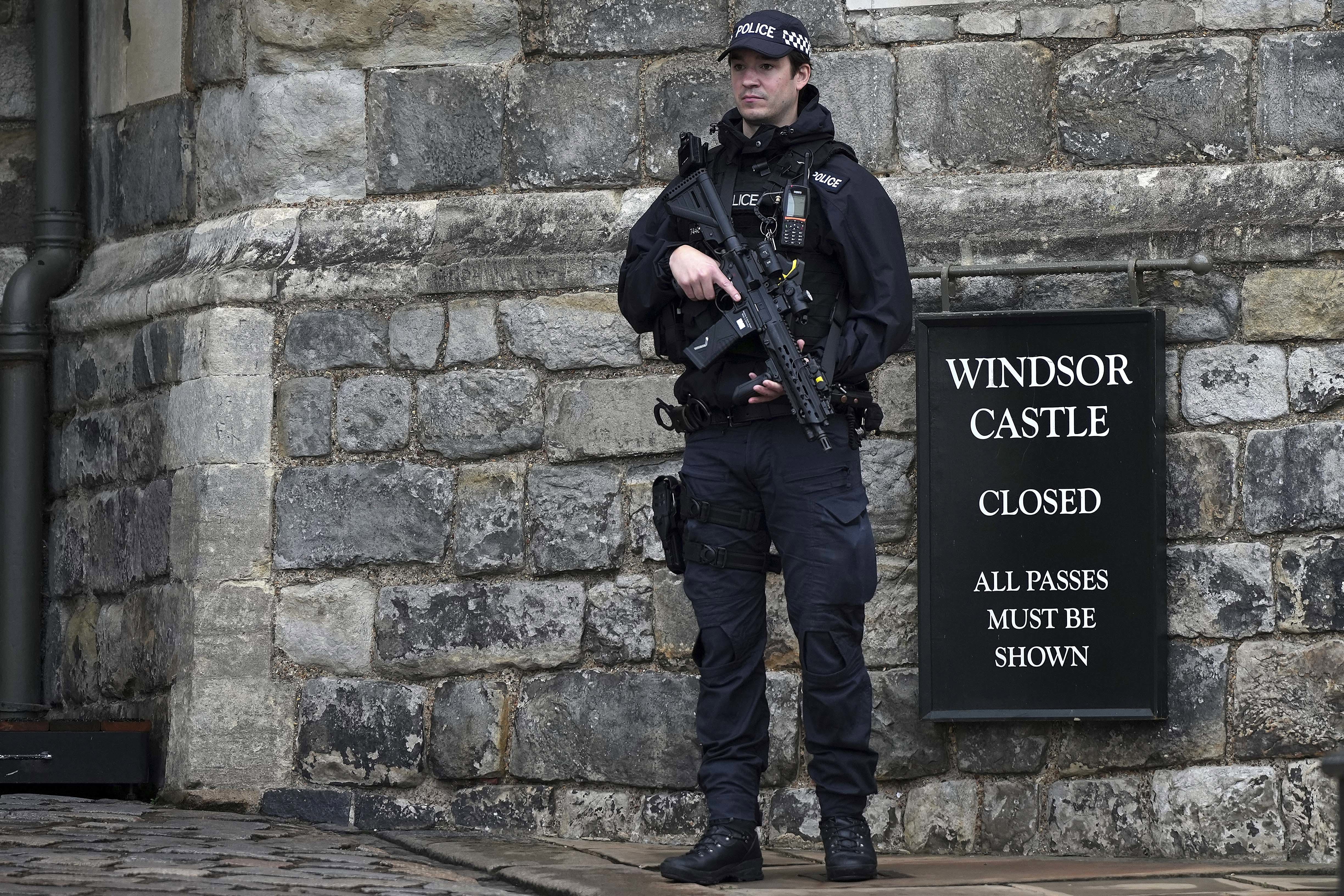 An armed police officer stands guard at the entrance to Windsor Castle.