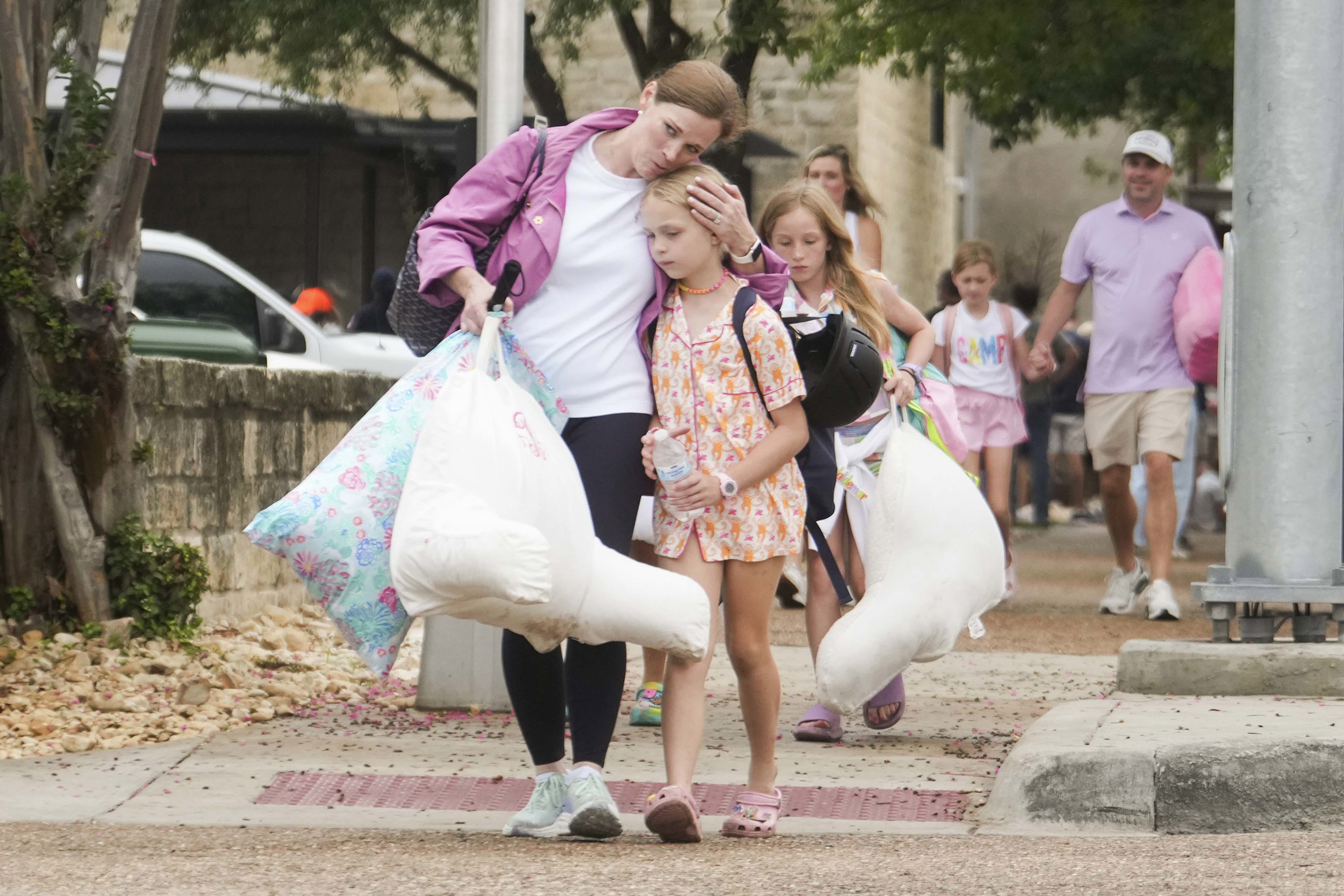 A woman and a child embrace after girls from Camp Waldemar, near the North fork of the Guadalupe River.