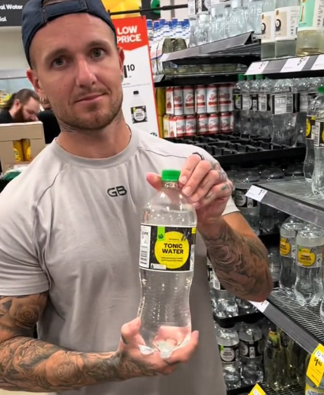 A man holds up a bottle of tonic water in the supermarket
