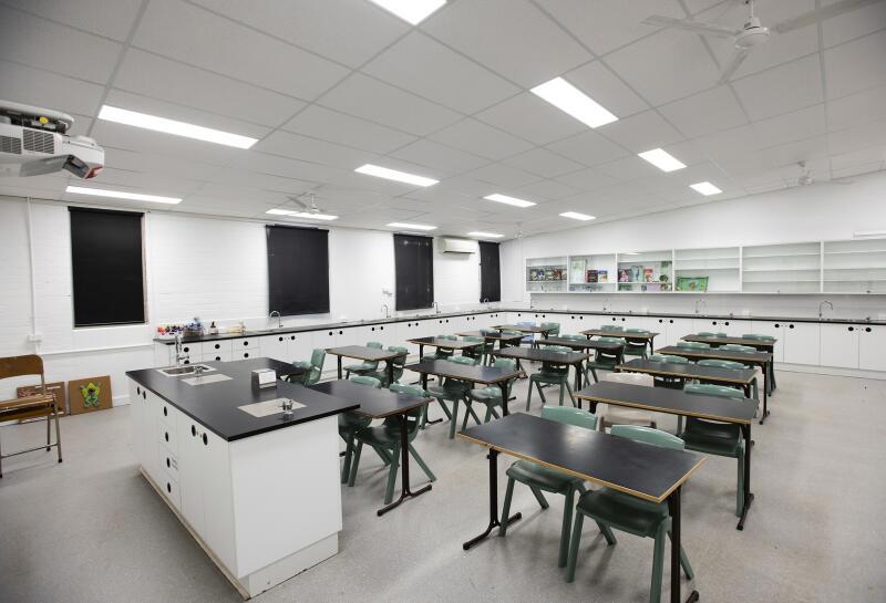 A classroom with white walls and black chairs and desks.