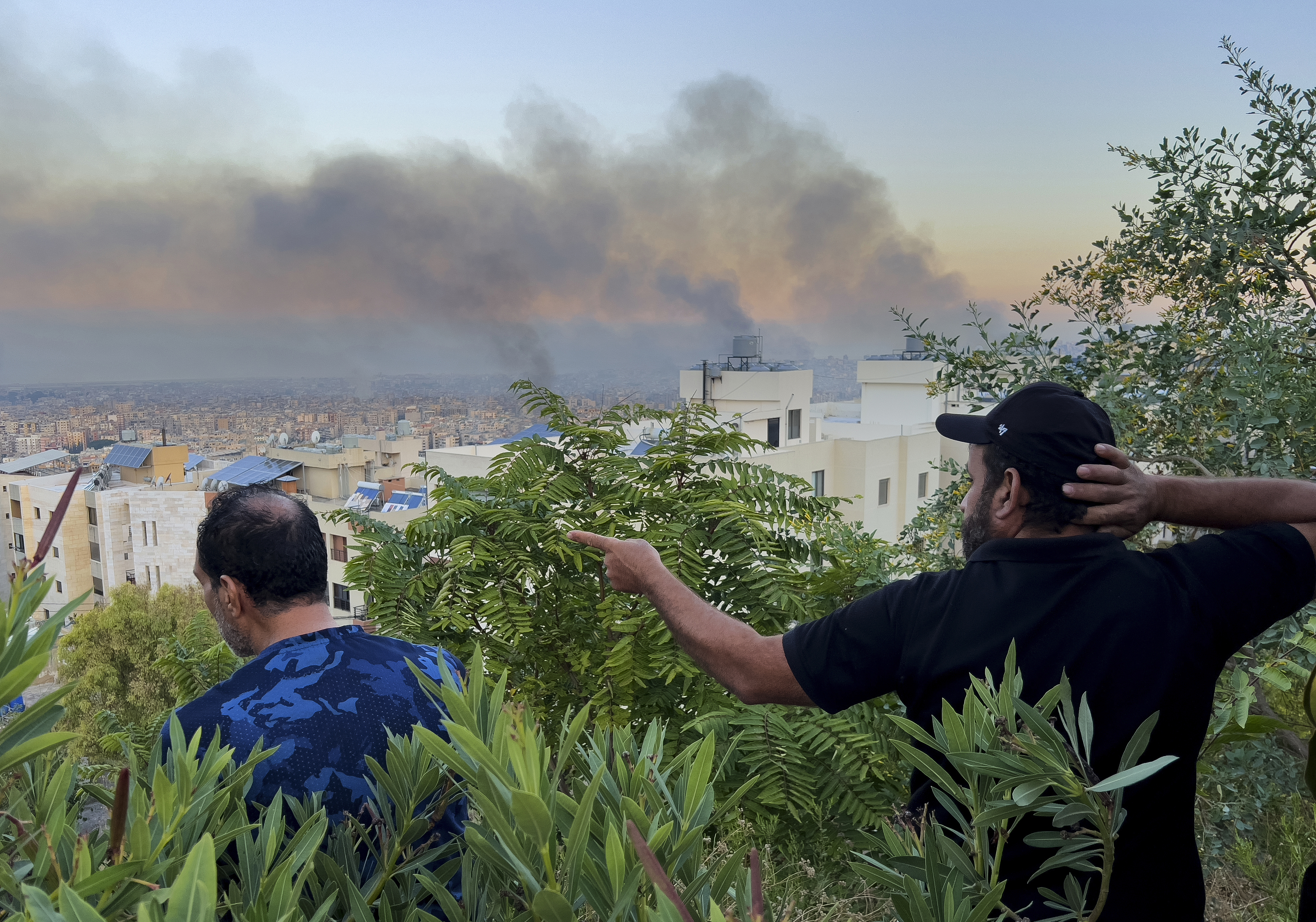 Lebanese citizens watch smoke rise from Israeli airstrikes in the southern suburbs of Beirut, Lebanon, Saturday, Sept. 28, 2024. 