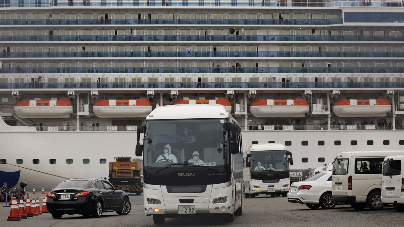 An ambulance leaves Yokohama Port where the Diamond Princess, back, is docked in Yokohama, near Tokyo, Friday, Feb. 14, 2020. The cruise ship is still carrying nearly 3,500 passengers and crew members under quarantine until at least Feb. 19. 