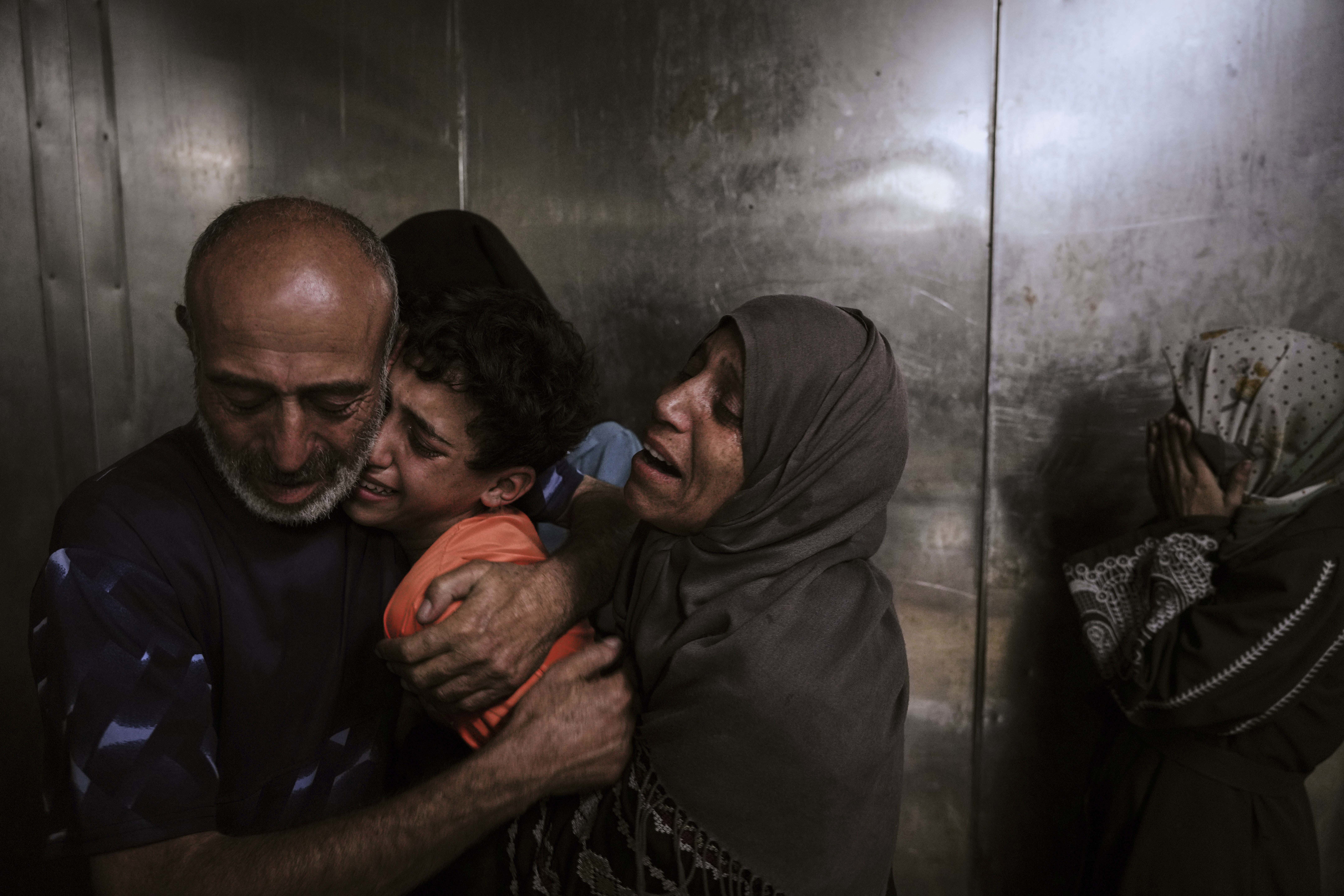 Raed Salem Aslyieh, left, from Jabaliya, hugs his relatives after the death of his son, Ahmed Raed Aslyieh, 18, who succumbed to injuries sustained in an Israeli strike that killed eight other family members four months earlier, worsened by a lack of proper treatment due to medicine shortages, at the morgue of Shifa Hospital in Gaza City, Aug. 6