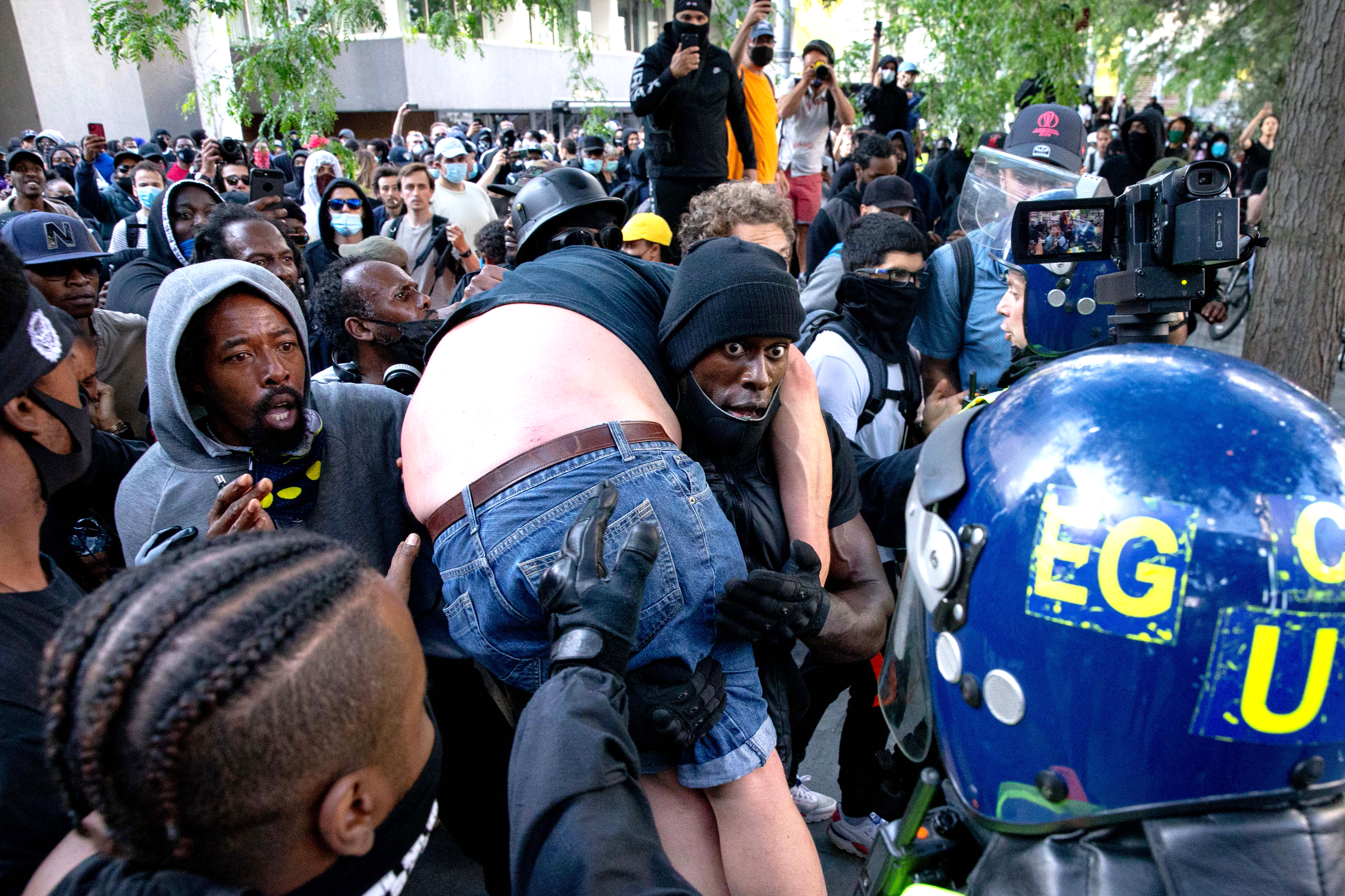 Patrick Hutchinson carries an injured man away after he was allegedly attacked by some of the crowd of protesters as police try to intervene on the Southbank near Waterloo station in London.