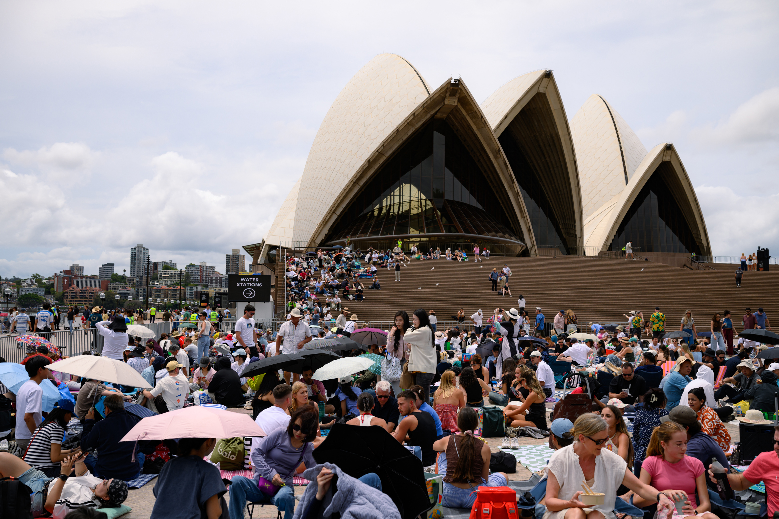SYDNEY, AUSTRALIA - DECEMBER 31: People gather at the Sydney Opera House in anticipation of the annual New Year's Eve fireworks display on December 31, 2025 in Sydney, Australia. Thousands will turn out to celebrate New Year's Eve in Sydney, as the Harbour Bridge lights up with fireworks. (Photo by George Chan/Getty Images)