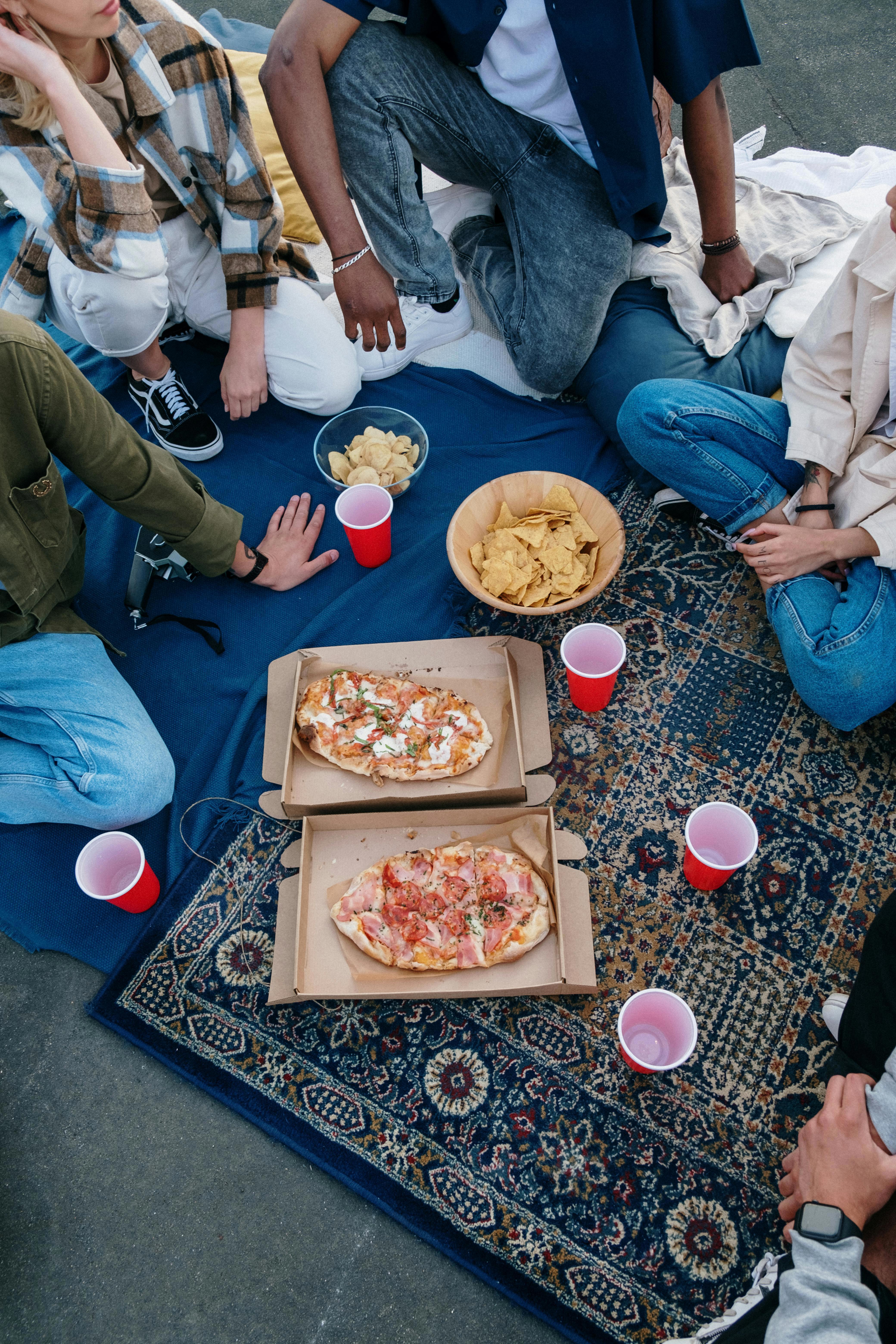 Stock image of friends eating pizza, chips and beer.