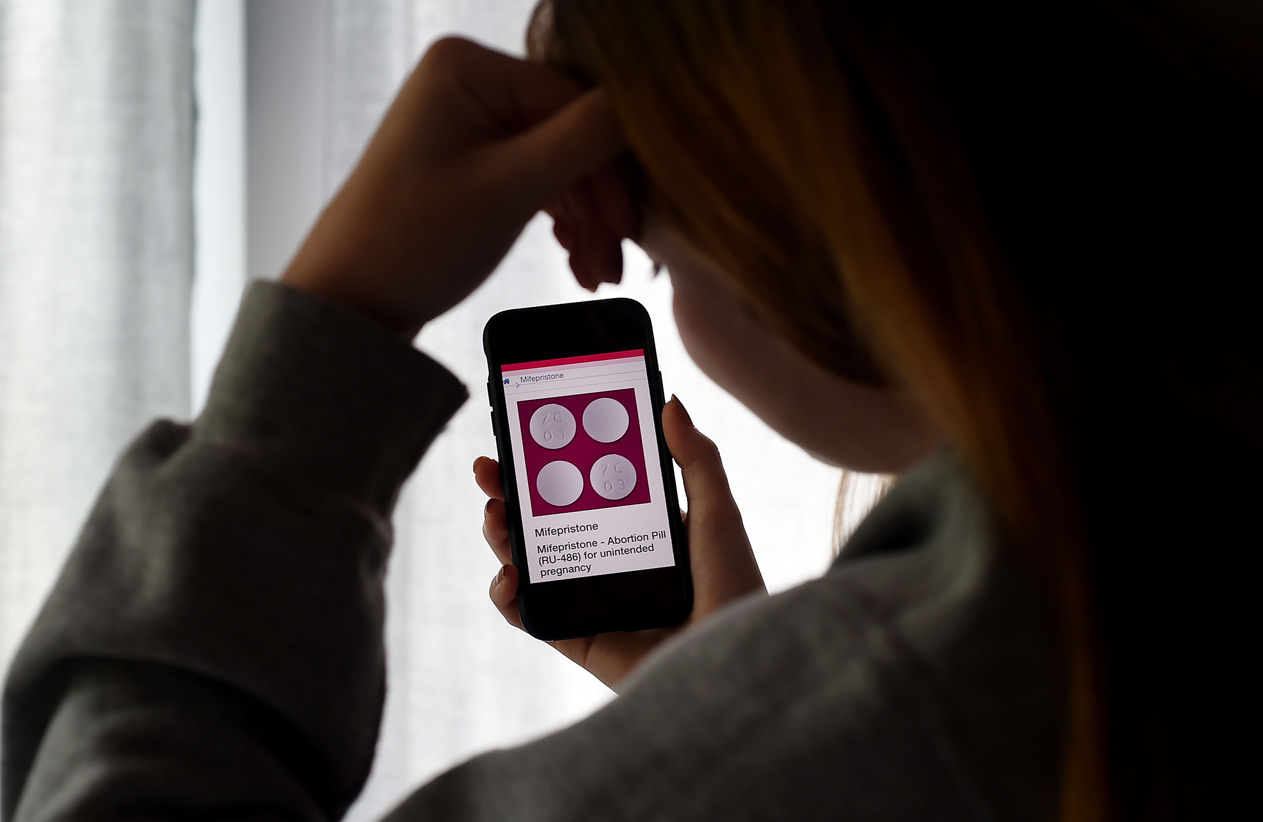 In this photo illustration, a person looks at an Abortion Pill (RU-486) for unintended pregnancy from Mifepristone displayed on a smartphone on May 8, 2020, in Arlington, Virginia. - One week after Sally realized she was pregnant, her home state Texas temporarily banned abortions, deeming them unnecessary elective procedures that were suspended because of the coronavirus crisis.So, the 34-year-old, whose name has been changed for this story to protect her privacy, took matters into her own hands