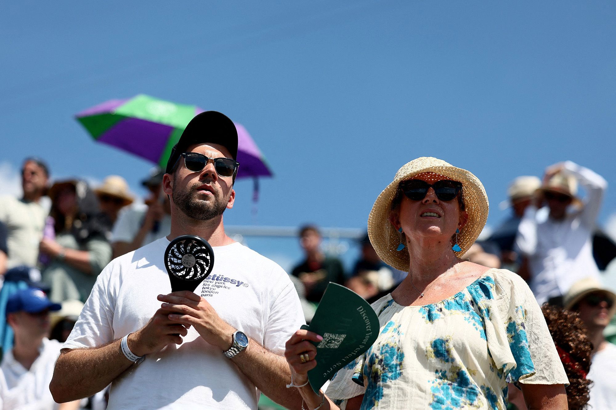 Wimbledon tennis spectators use handheld fans to cool themselves down during the first round match between Russia's Daniil Medvedev and France's Benjamin Bonzi in London on June 30, 2025.
