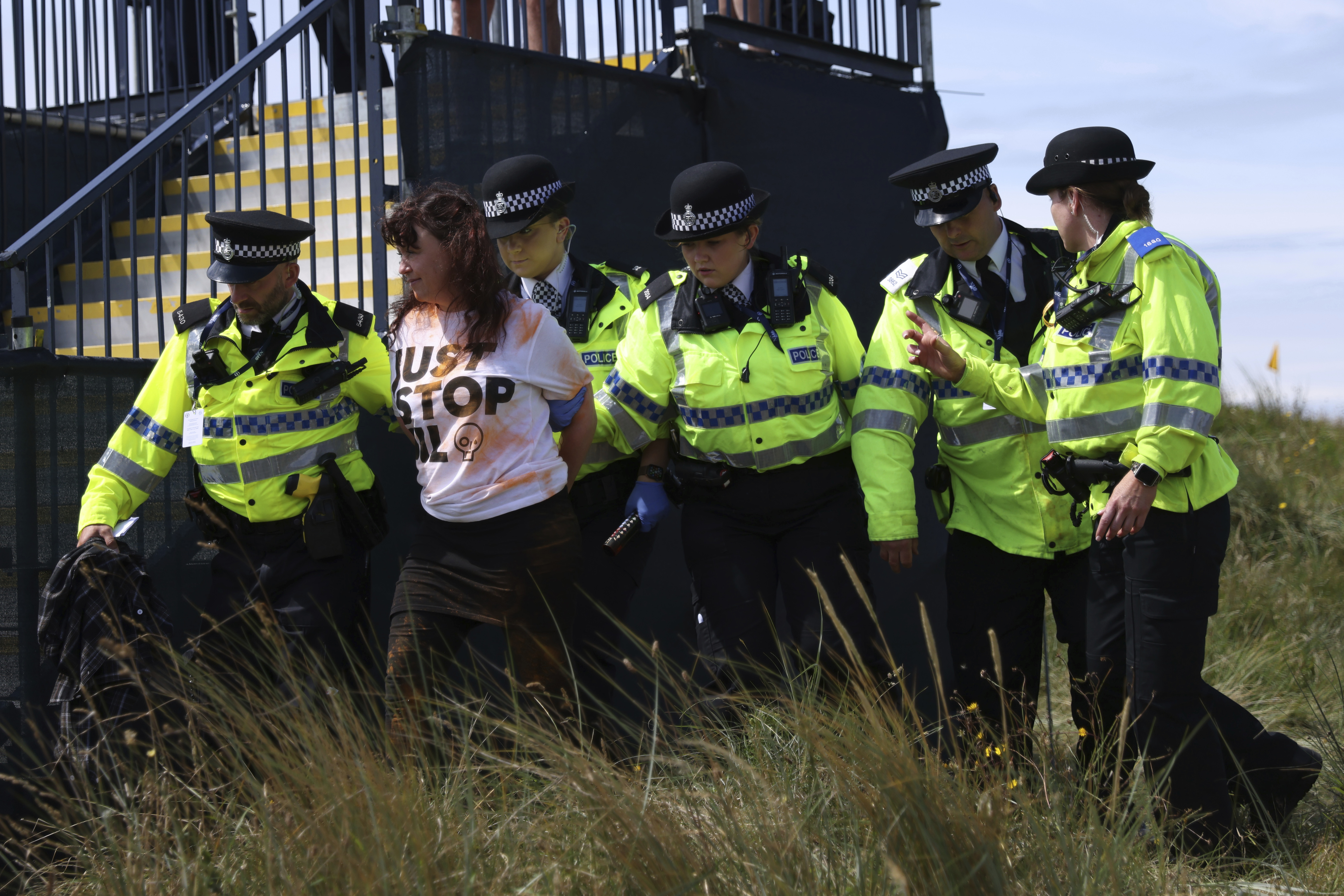 A Just Stop Oil protester is led away by police and security near the 17th hole during the second day of the British Open Golf Championships at the Royal Liverpool Golf Club in Hoylake, England, Friday, July 21, 2023 