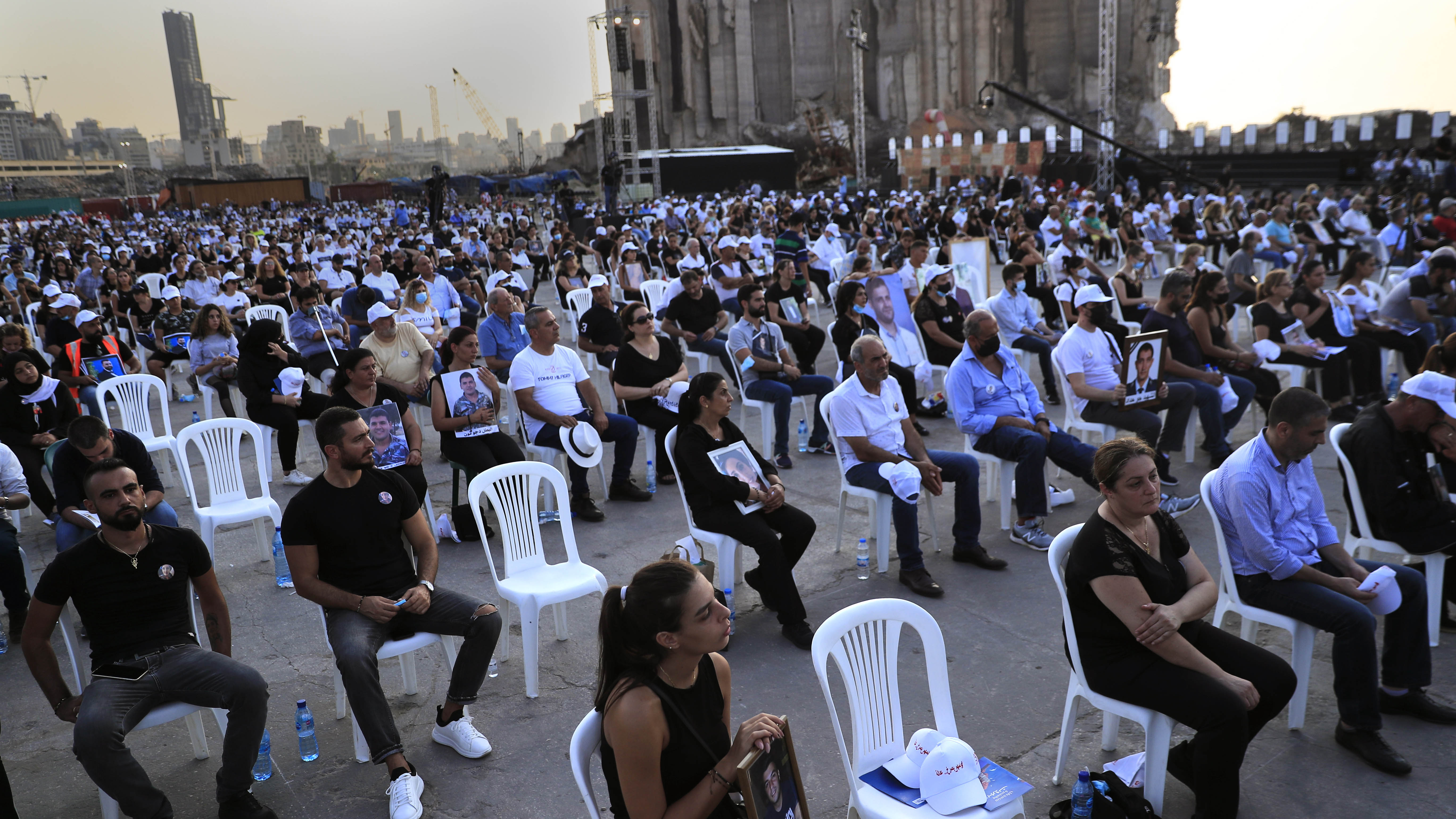 Relatives of victims who were killed in the massive blast last year at the Beirut port holds their portraits as they attend a Mass held to commemorate the first year anniversary of the deadly blast, at the Beirut port, Lebanon.