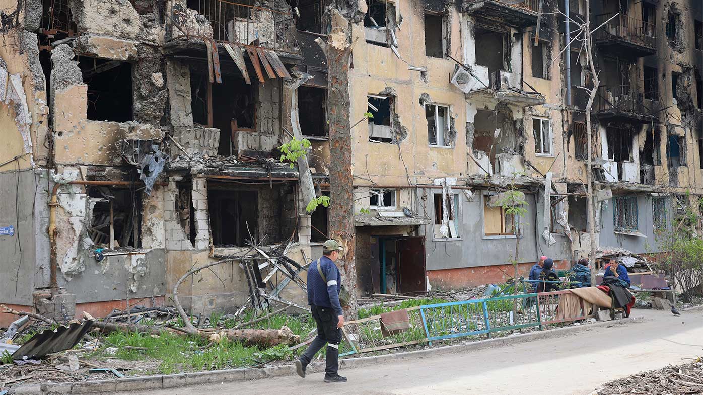 A man walks past a destroyed apartment building in Mariupol.