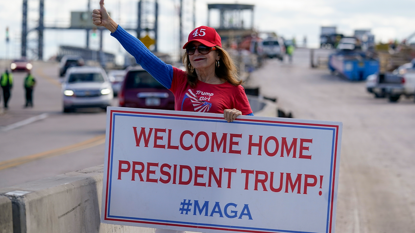 A supporter of President Donald Trump waits for the motorcade on the road to Mar-a-Lago, Trumps Palm Beach estate, on Wednesday, Jan. 20, 2021, in West Palm Beach, Fla. (AP Photo/Lynne Sladky)