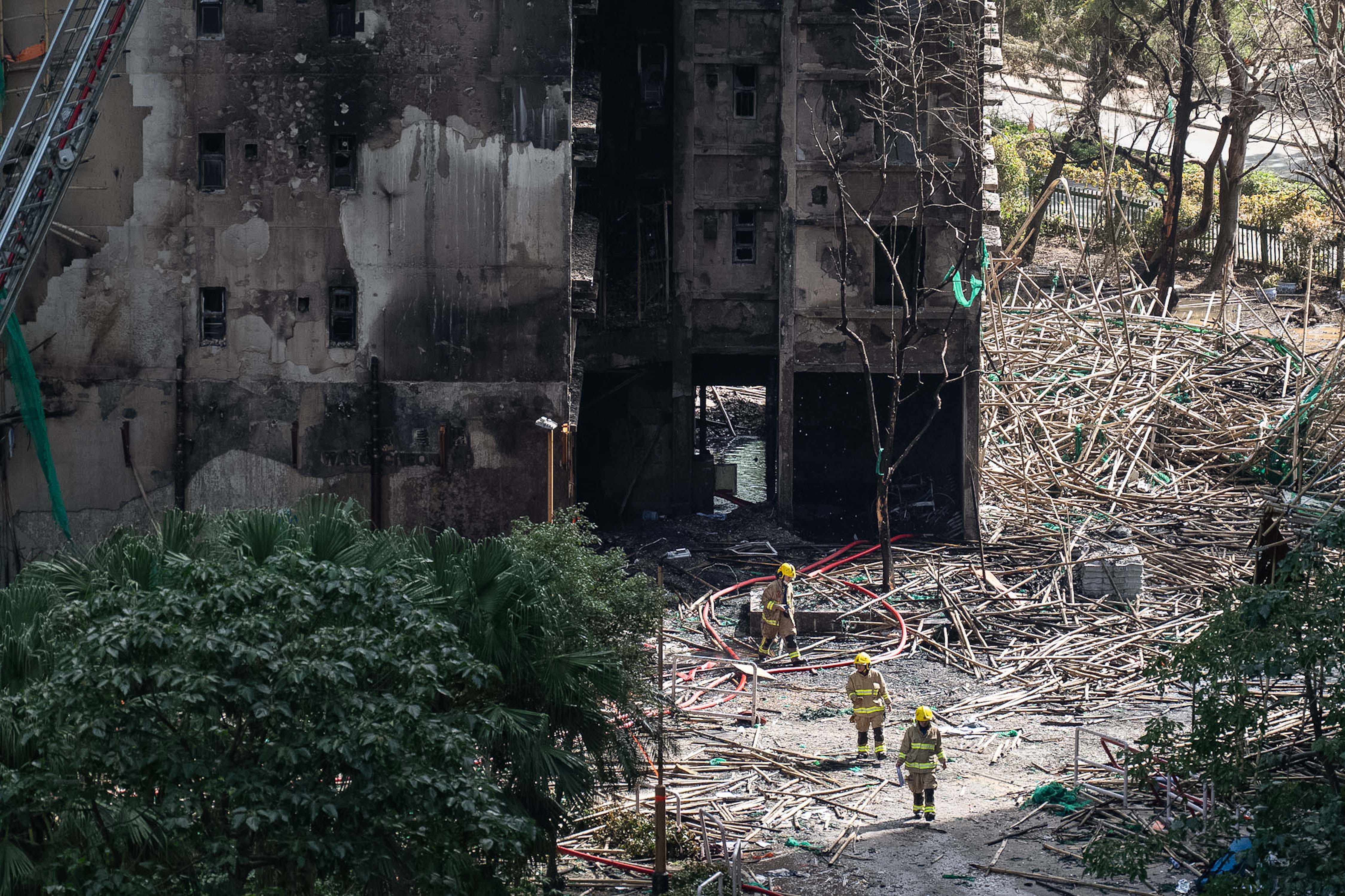 Firefighters walk through the burned buildings after the deadly fire in Hong Kong's New Territories.
