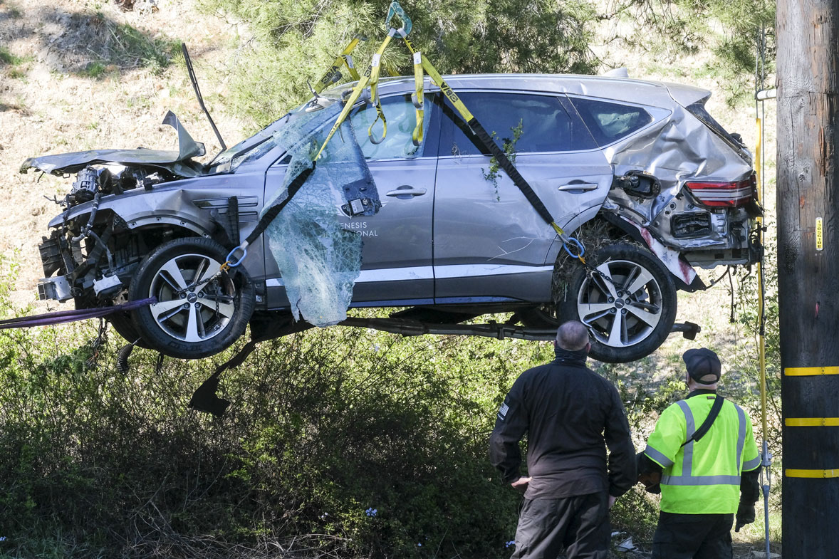 A crane is used to lift a vehicle following a rollover accident involving golfer Tiger Woods, Tuesday, Feb. 23, 2021, in the Rancho Palos Verdes suburb of Los Angeles. Woods suffered leg injuries in the one-car accident and was undergoing surgery, authorities and his manager said. 