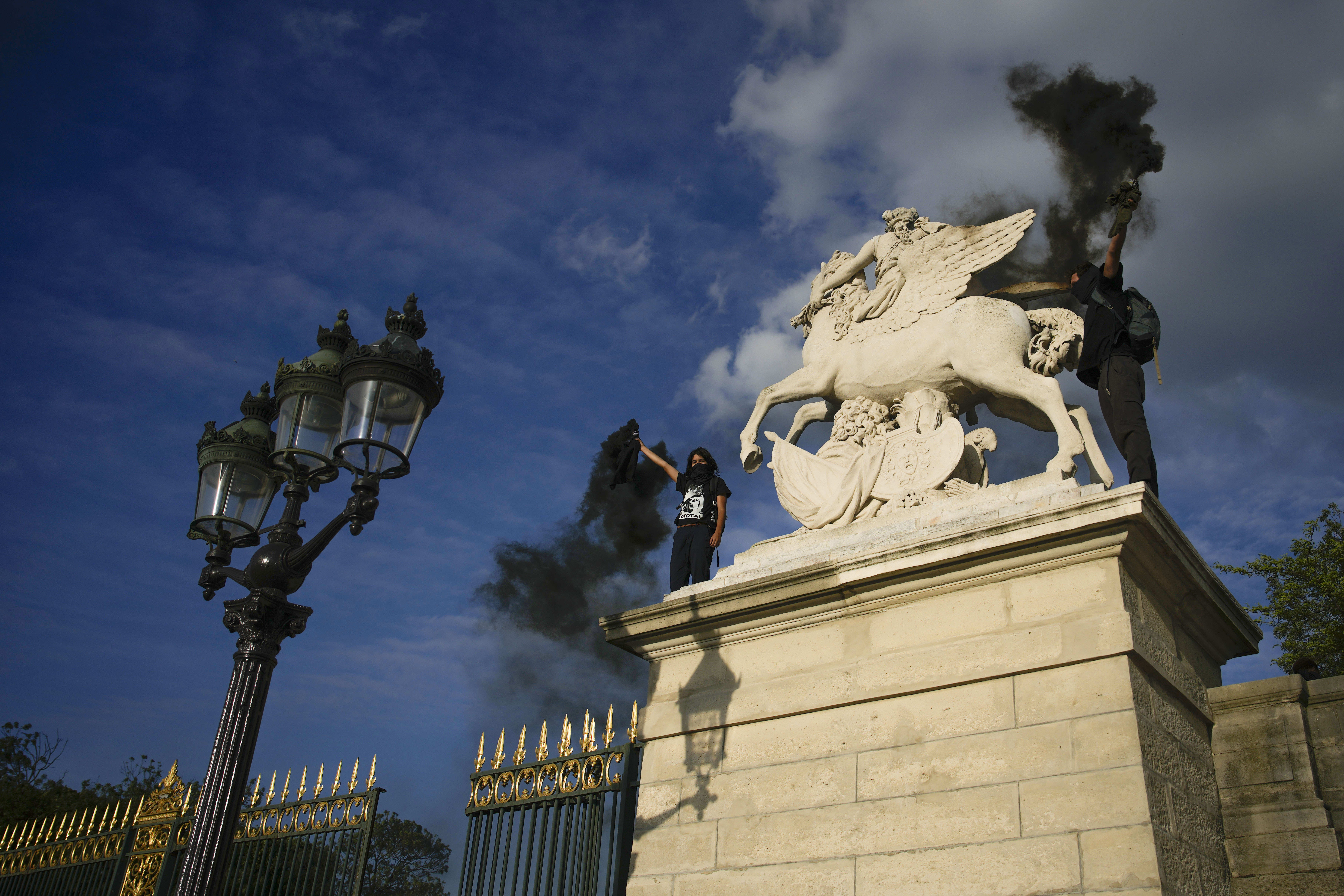 Youth light flares on Place de la Concorde during a protest in Paris, France, Friday, June 30, 2023. French President Emmanuel Macron urged parents on Friday to keep teenagers at home and proposed restrictions on social media to quell rioting spreading across France over the fatal police shooting of a 17-year-old driver. (AP Photo/Lewis Joly)
