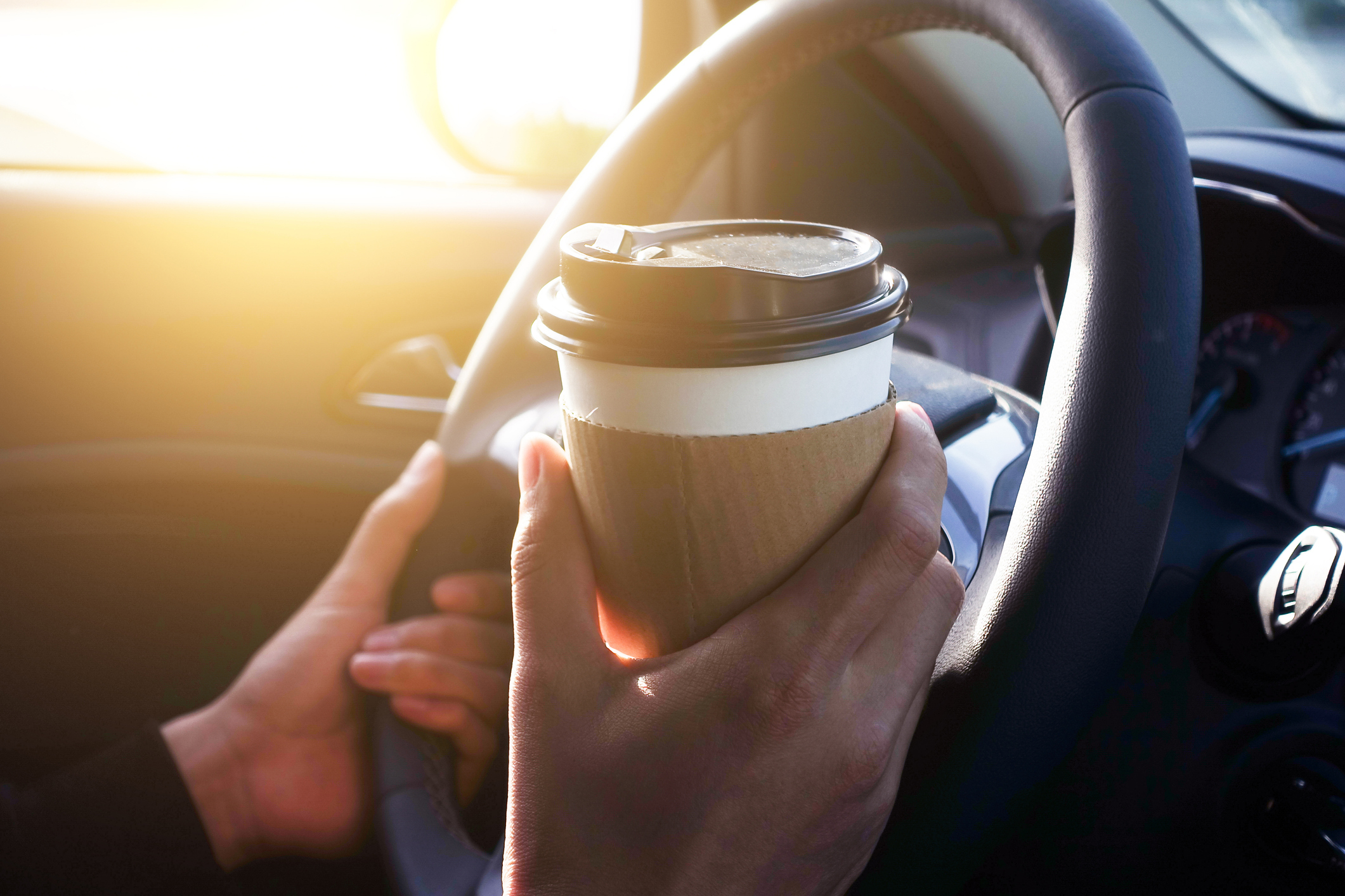 Man holding coffee in car