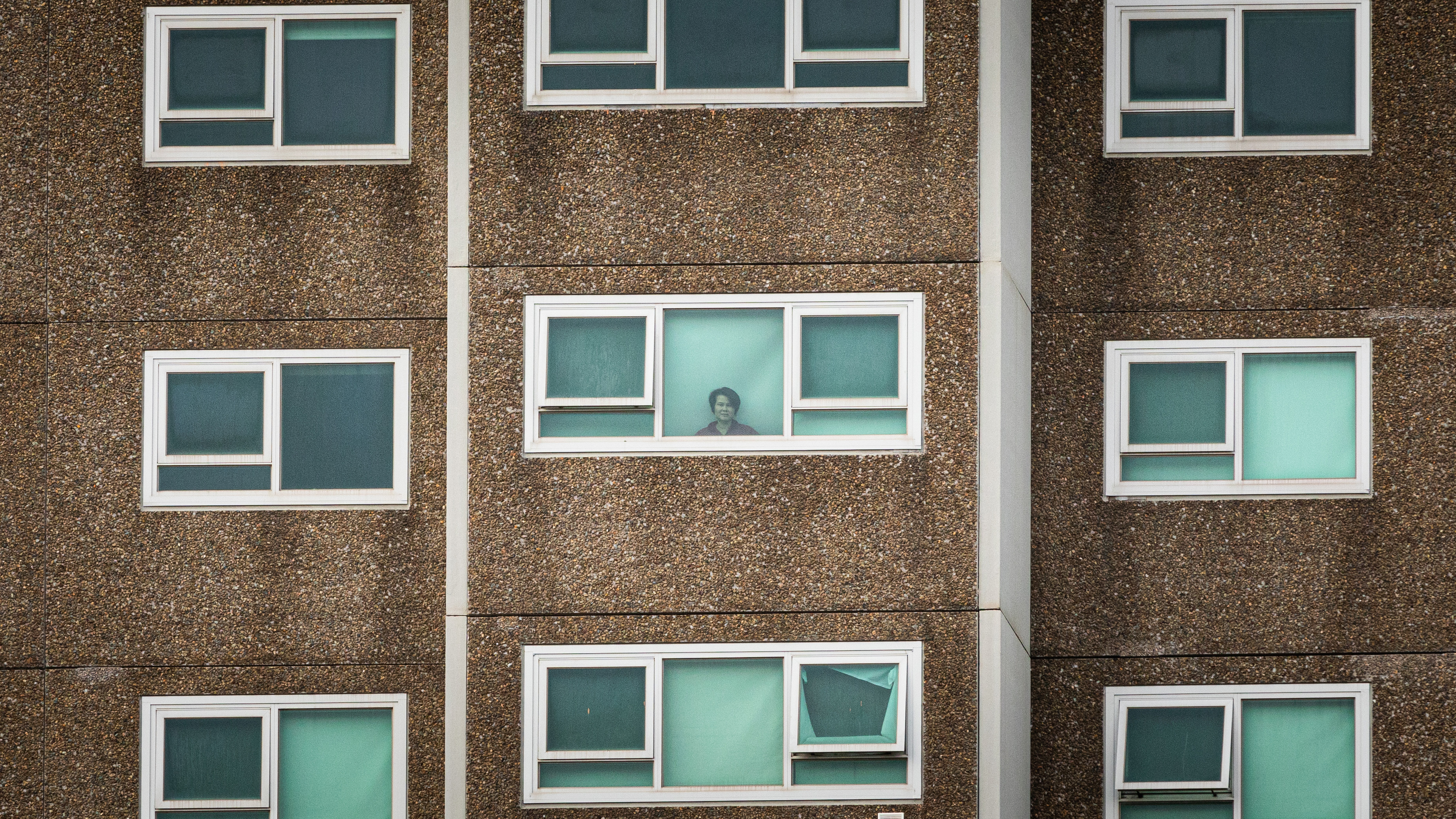 A lone woman is seen looking out the window of her apartment at the North Melbourne Public housing flats on July 05, 2020 in Melbourne, Australia. Nine public housing estates have been placed into mandatory lockdown and two additional suburbs are under stay-at-home orders as authorities work to stop further COVID-19 outbreaks in Melbourne. 