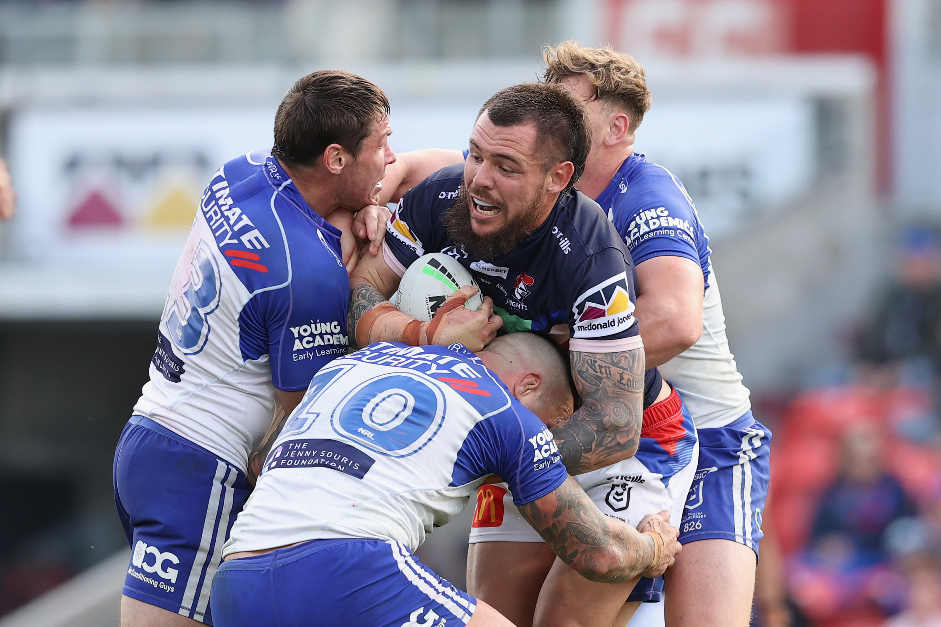 David Klemmer of the Knights is tackled by Bulldogs players.