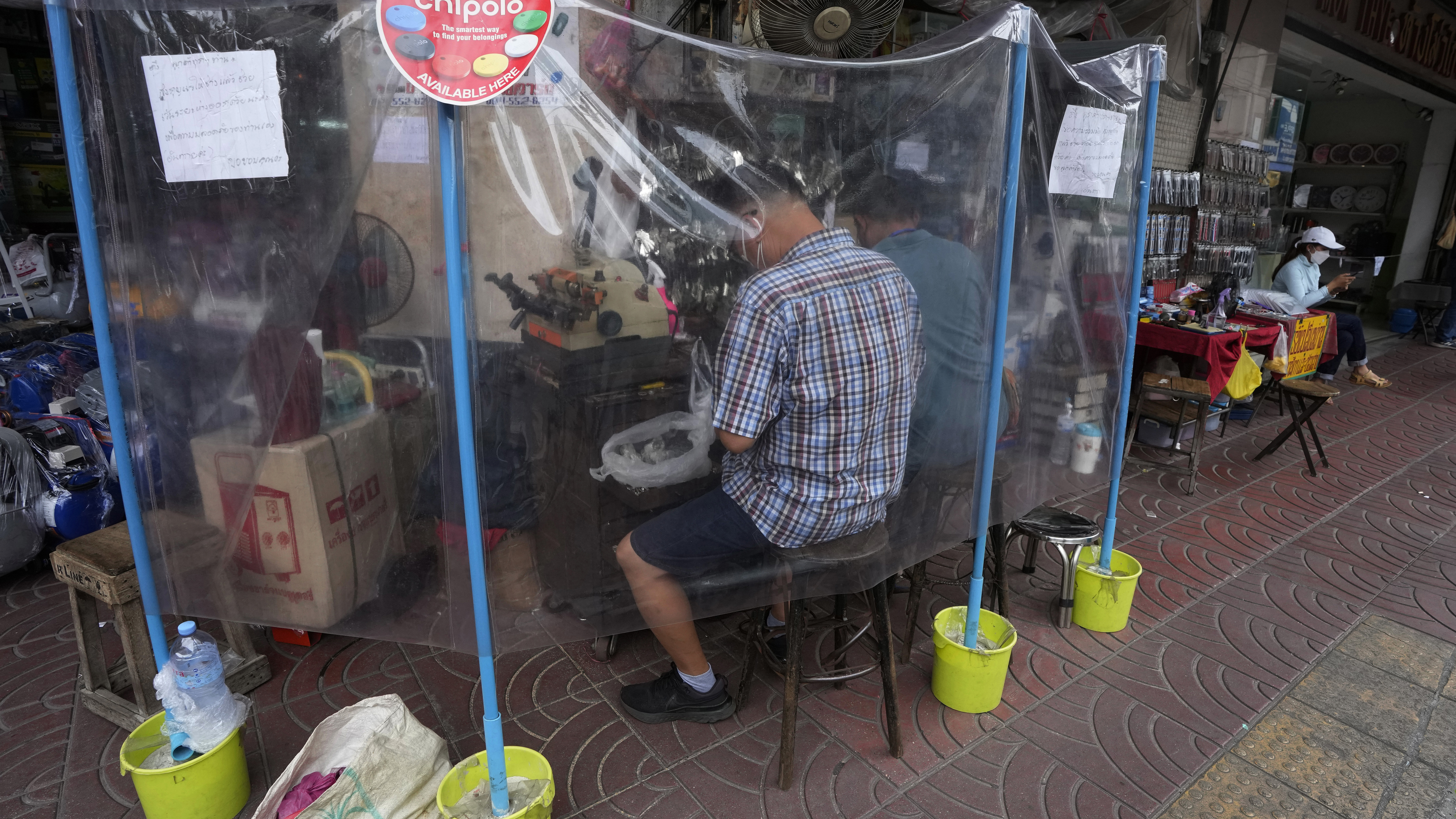 Two locksmiths provided services to customers from behind protective plastic sheets to help curb the spread of the COVID-19 in Bangkok.