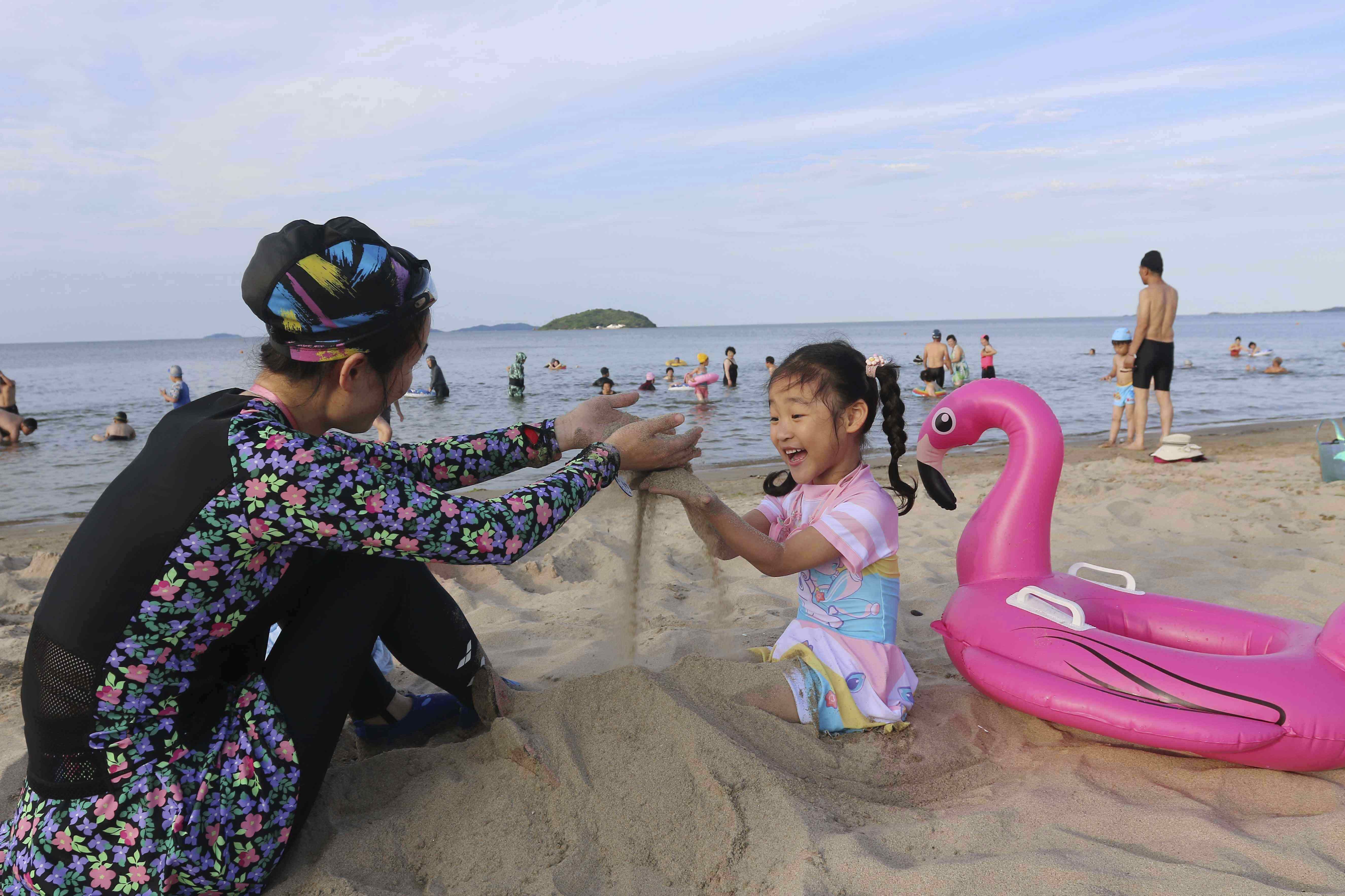 A girl and her mother play on the beach at the the Wonsan-Kalma resort in Wonsan, Kangwon Province, North Korea, Tuesday, July 1, 2025. (AP Photo/Jon Chol Jin)