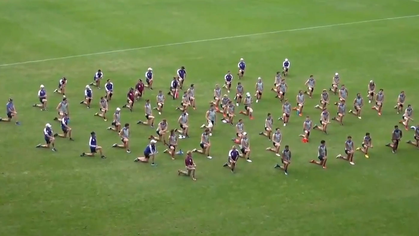Brisbane Lions players and staff take a knee