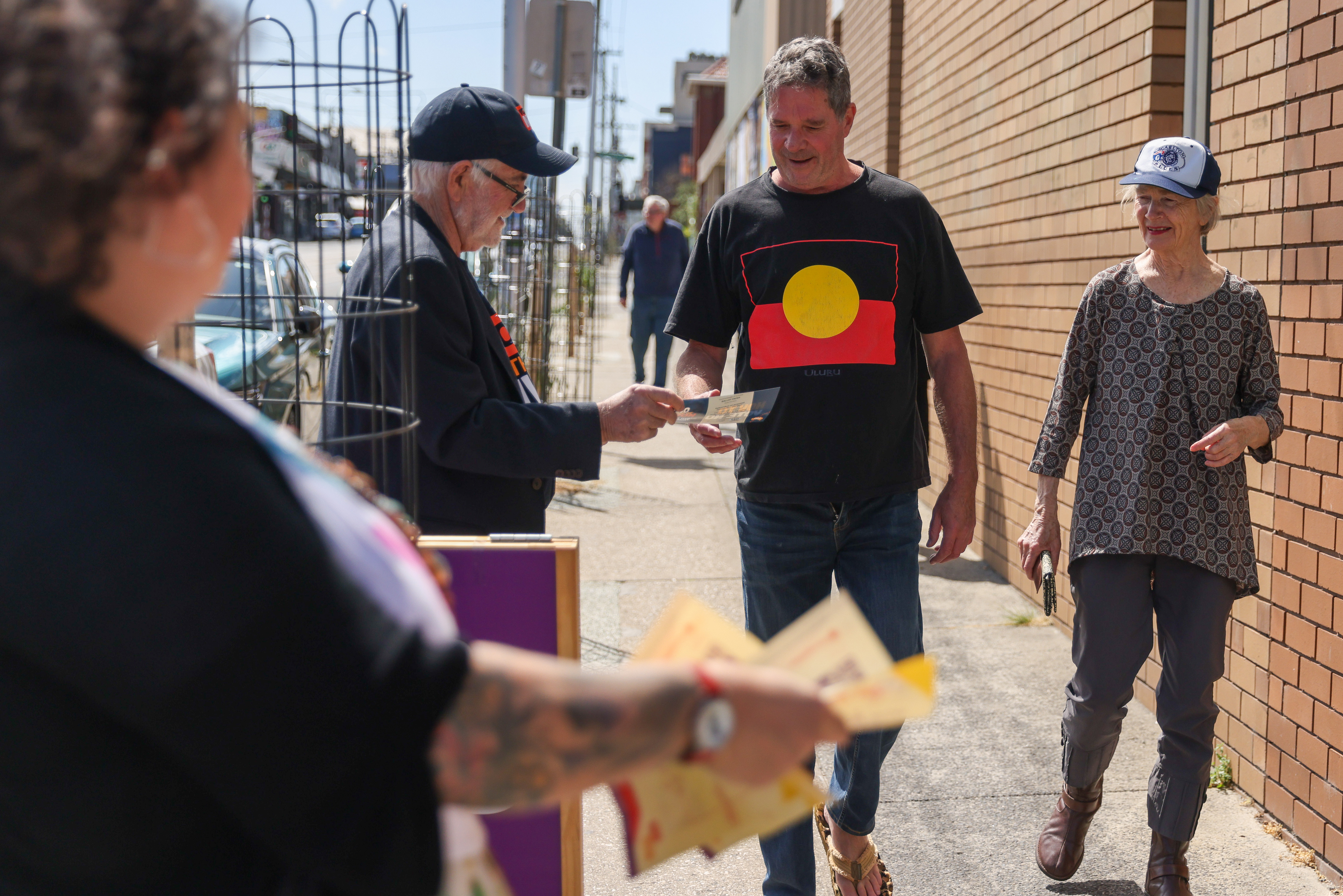 Volunteers hand "how to vote" cards outside a polling booth