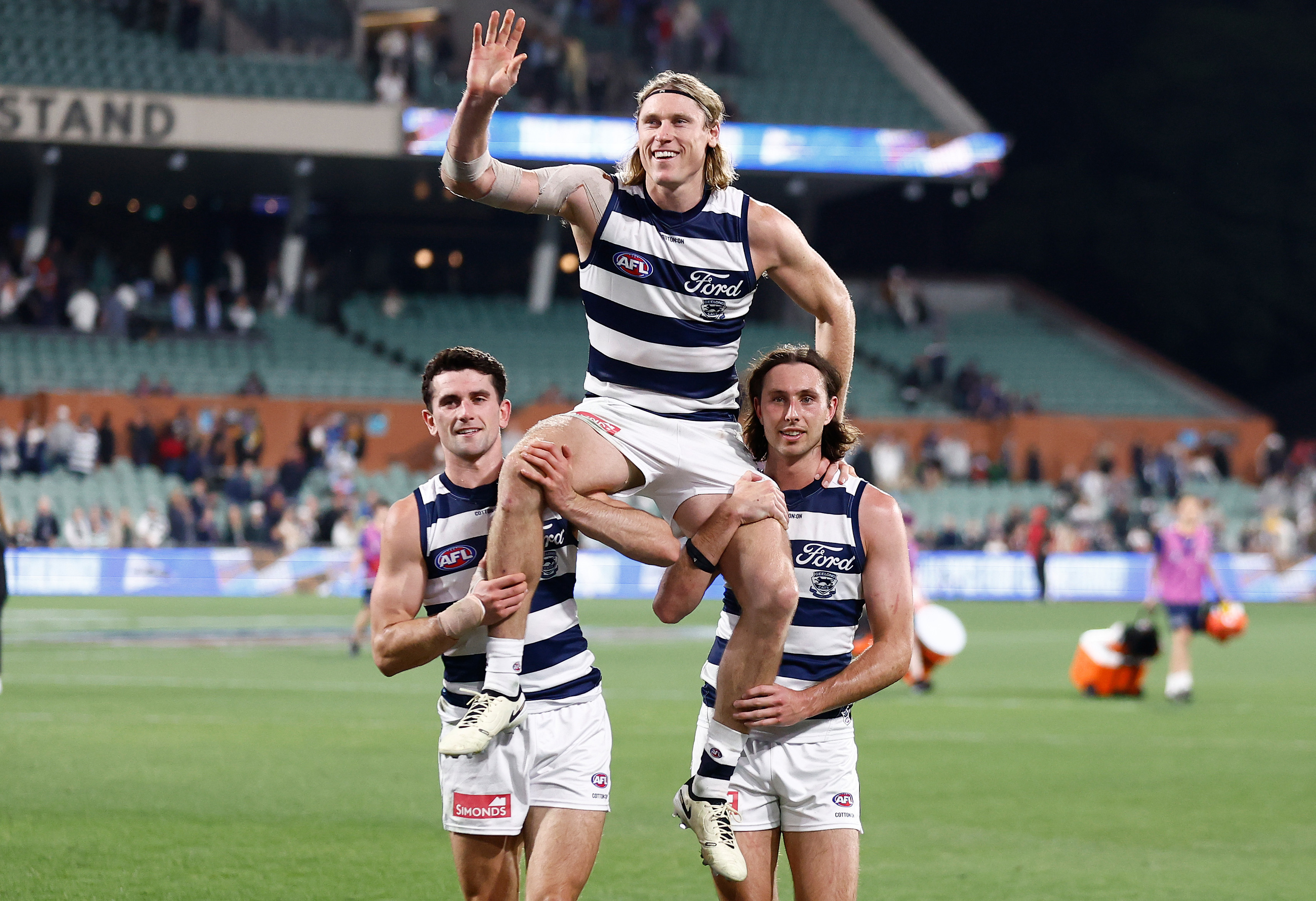 Mark Blicavs is chaired off by Mark O'Connor and Jack Henry.