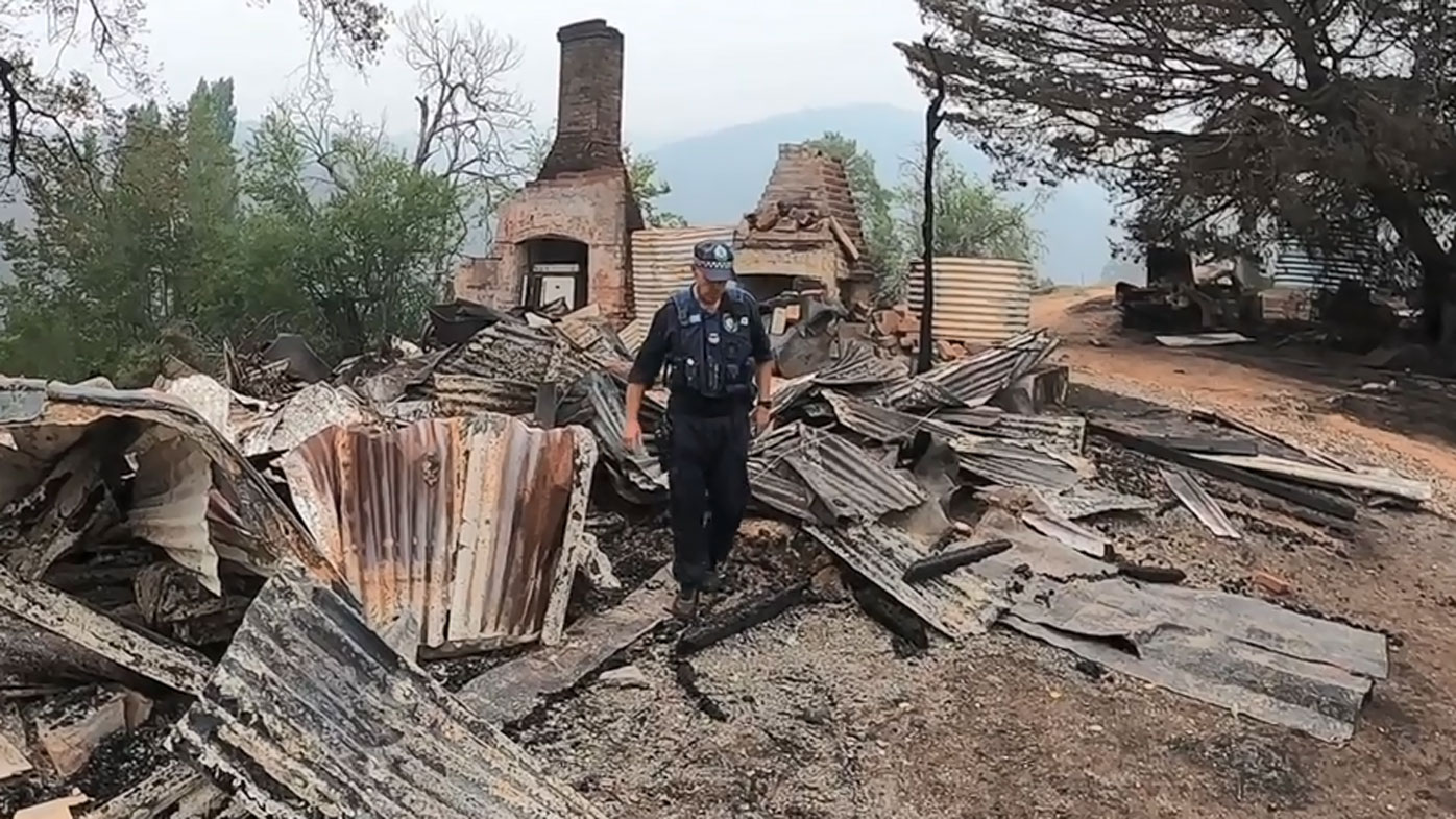 A police officer inspects one of the burnt out buildings on Colin's property.