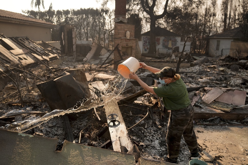 ARCHIVO - Nancy Belanger vierte agua en la propiedad de un vecino devastada por el incendio de Palisades en el vecindario Pacific Palisades de Los Ángeles, el jueves 9 de enero de 2025. (Foto AP/Jae C. Hong, archivo)