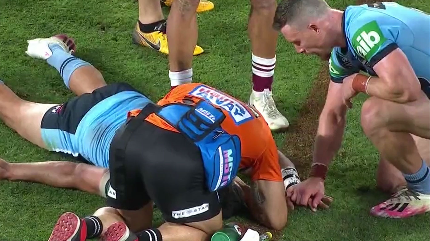 Damien Cook holds Cody Walker's hand while trainers tend to the knocked-out Blues playmaker. (Nine)