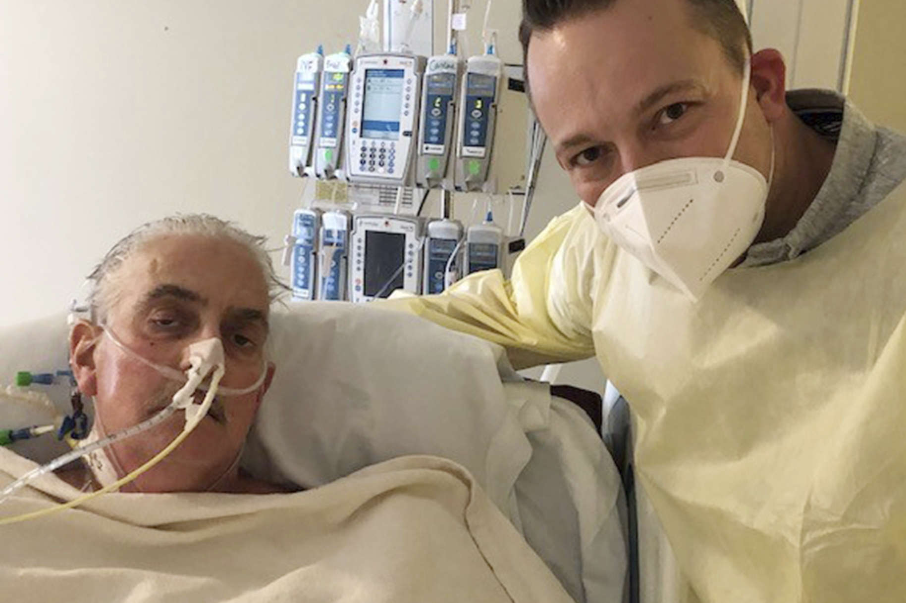David Bennett Jr. (right) stands next to his father's hospital bed in Baltimore on January 12, 2022, five days after doctors transplanted a pig heart into Bennett Sr., in a last-ditch effort to save his life. 