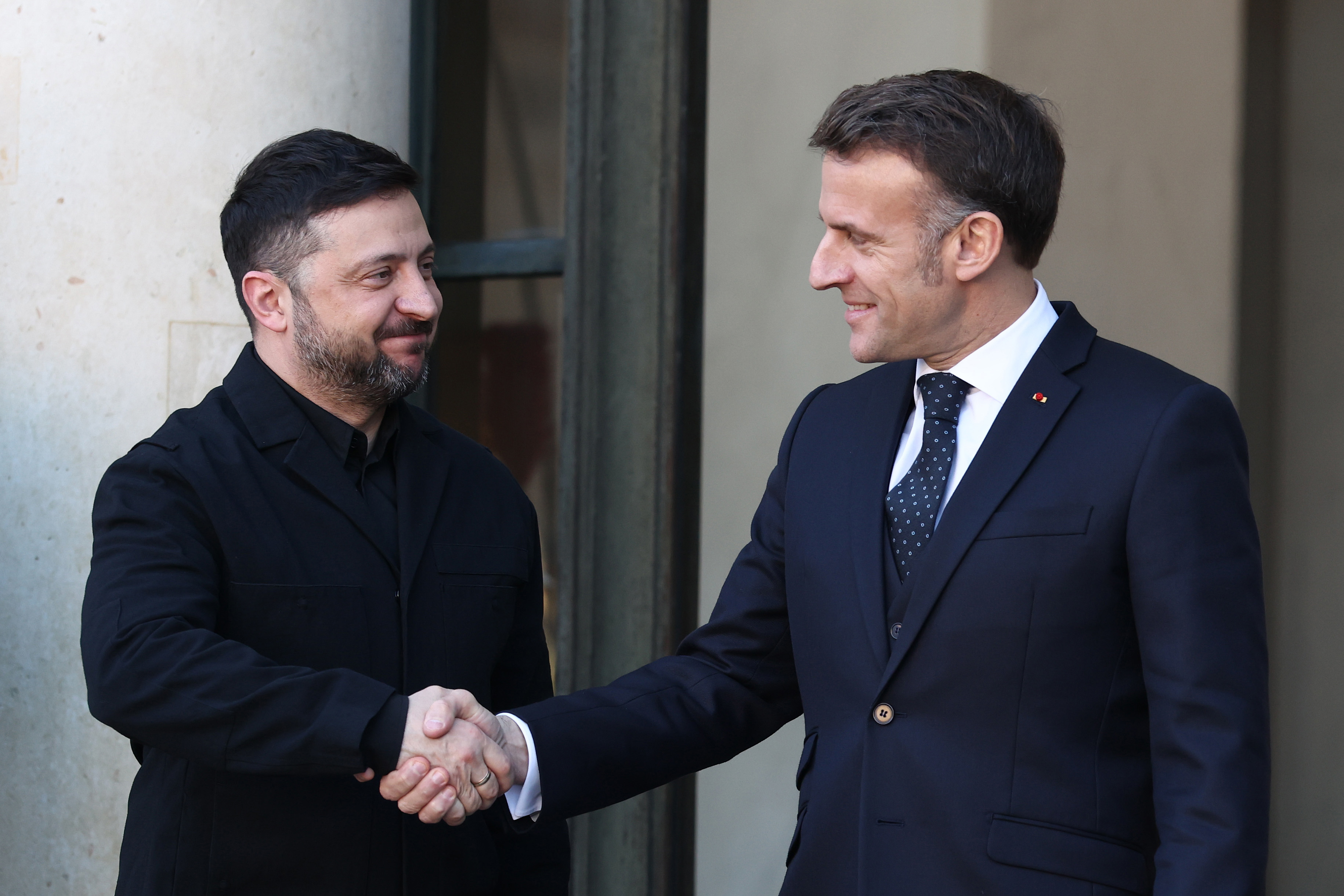 PARIS, FRANCE - JANUARY 06: French President Emmanuel Macron (R) greets Ukrainian President Volodymyr Zelensky upon his arrival at the Elysee Palace on January 06, 2026 in Paris, France. Leaders from around 30 countries are gathering in Paris to discuss military support for Ukraine, amid ongoing negotiations on a US-brokered peace plan to end Russia's war in Ukraine. (Photo by Tom Nicholson/Getty Images)