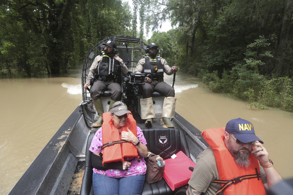 Texas Parks & Wildlife Department game wardens use a boat to rescue residents from floodwaters in Liberty County, Texas, on Saturday, May 4, 2024. (AP Photo/Lekan Oyekanmi)