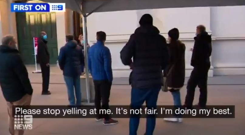 A health worker urges calm outside the Royal Exhibition Centre in Melbourne in Victoria.